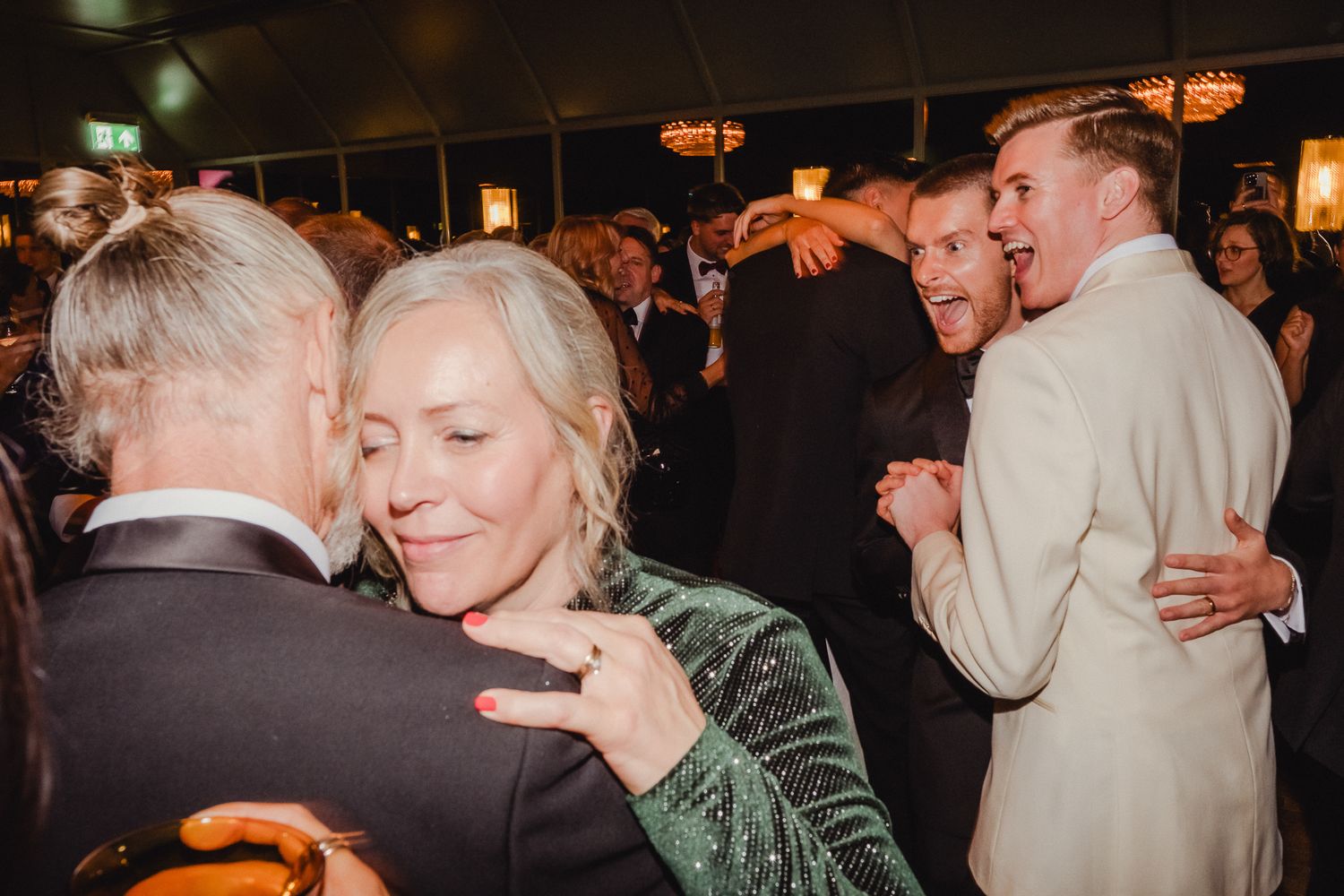 People dancing together at a dimly lit social event with warm lighting.