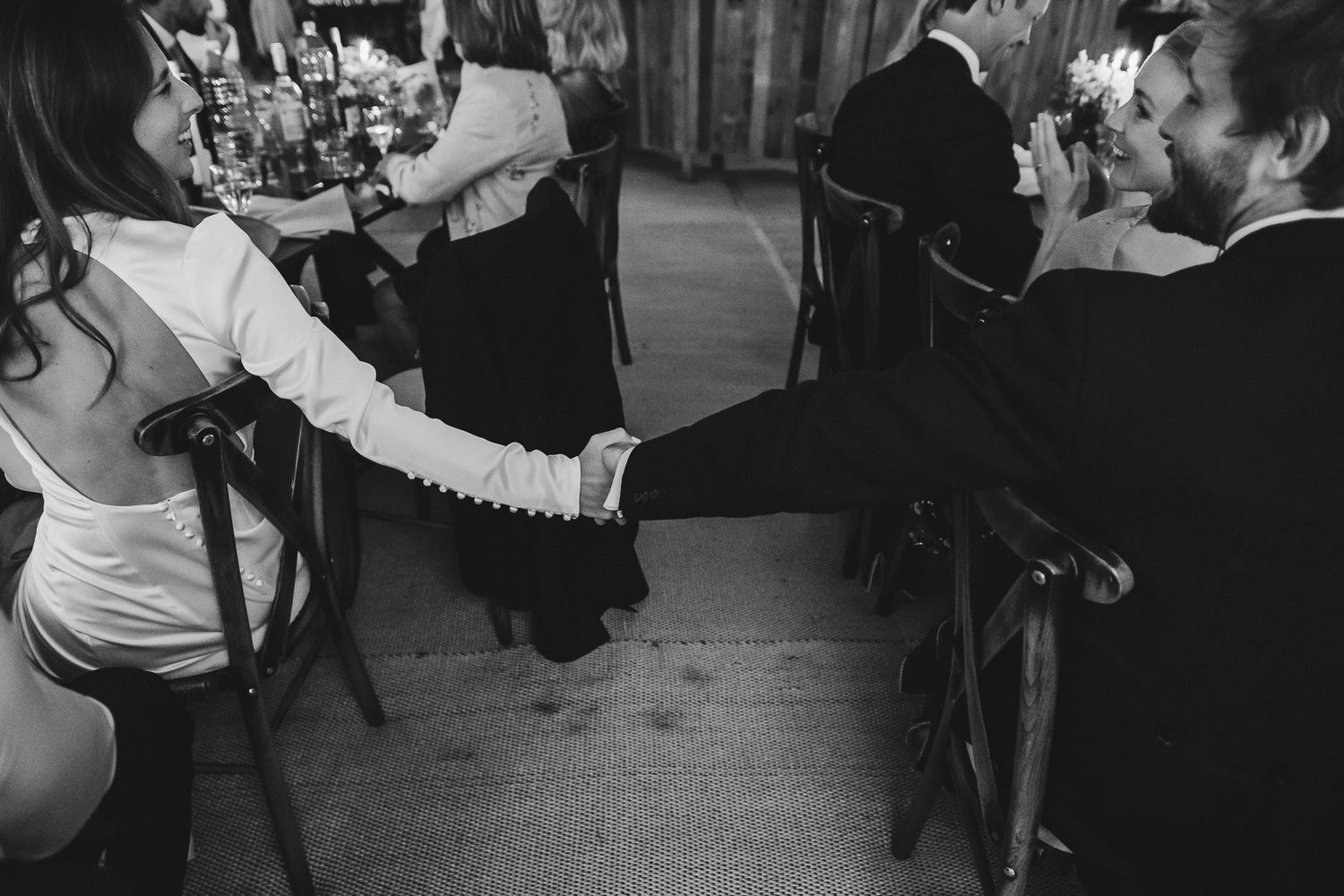 Wedding guests dancing together in a dimly lit reception venue with joyful energy and movement.