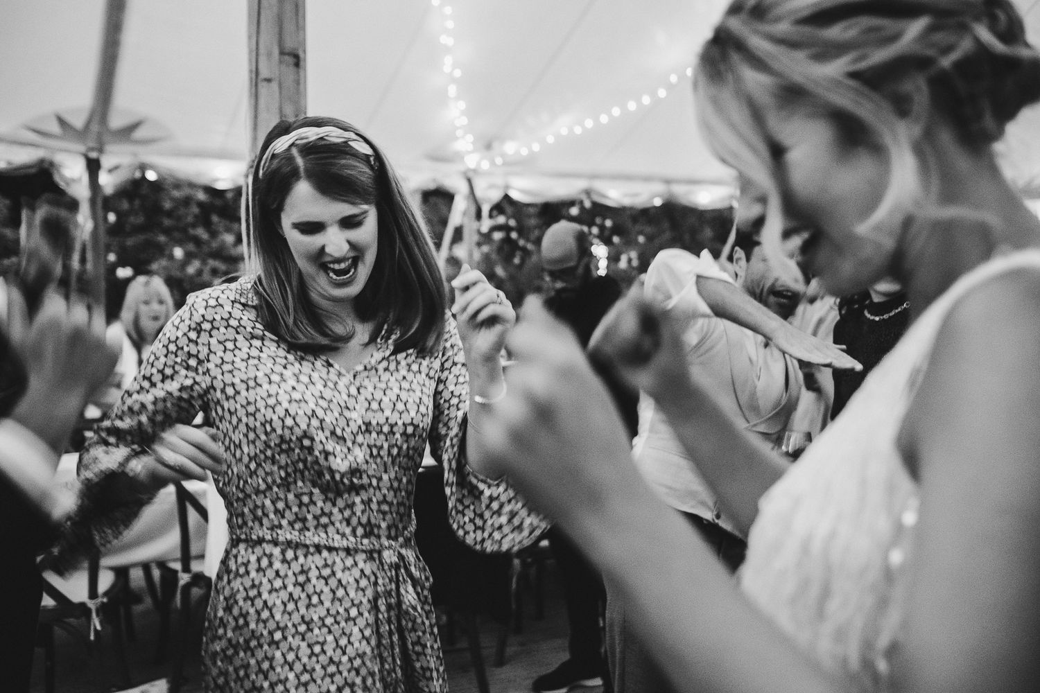 Black and white photo of wedding guests dancing and celebrating at reception.