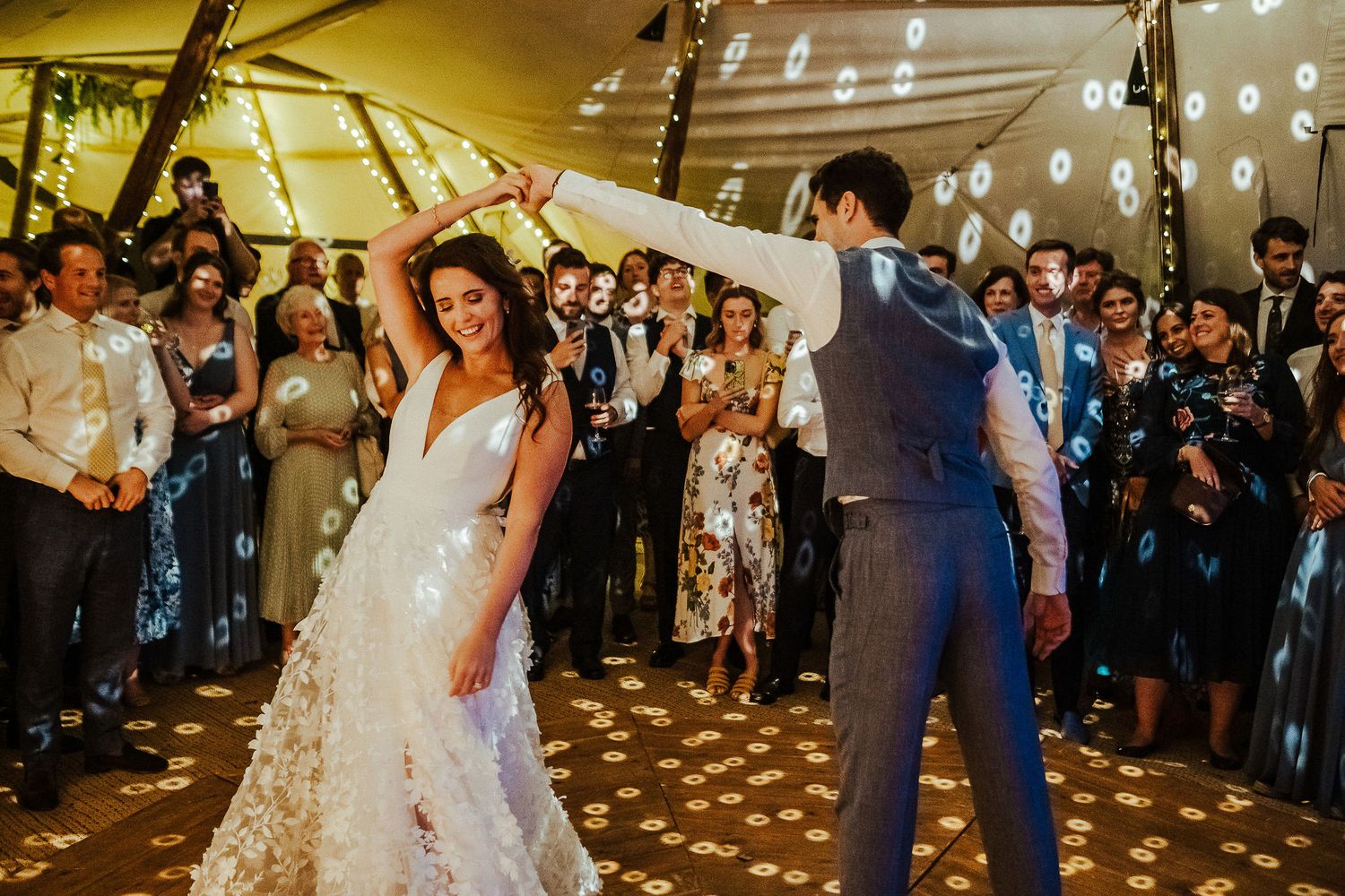 String lights illuminate a romantic dance moment at an outdoor wedding celebration.