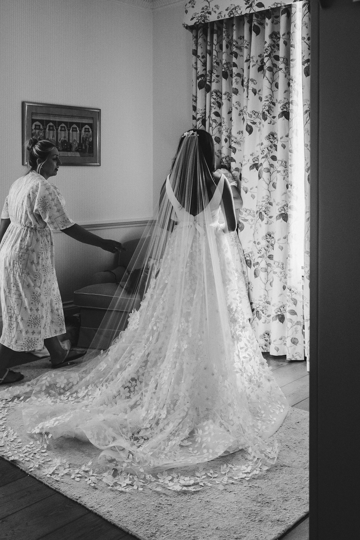 A stunning cathedral length lace wedding veil trails across a carpeted floor.
