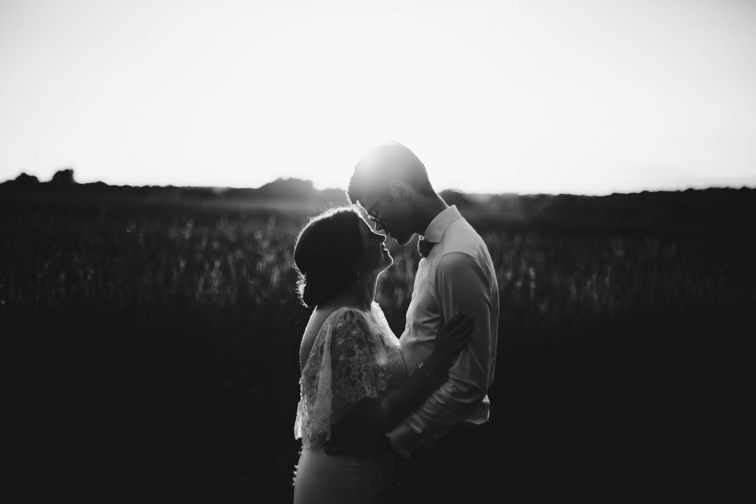 A romantic silhouette of a couple embracing against a sunset backdrop.