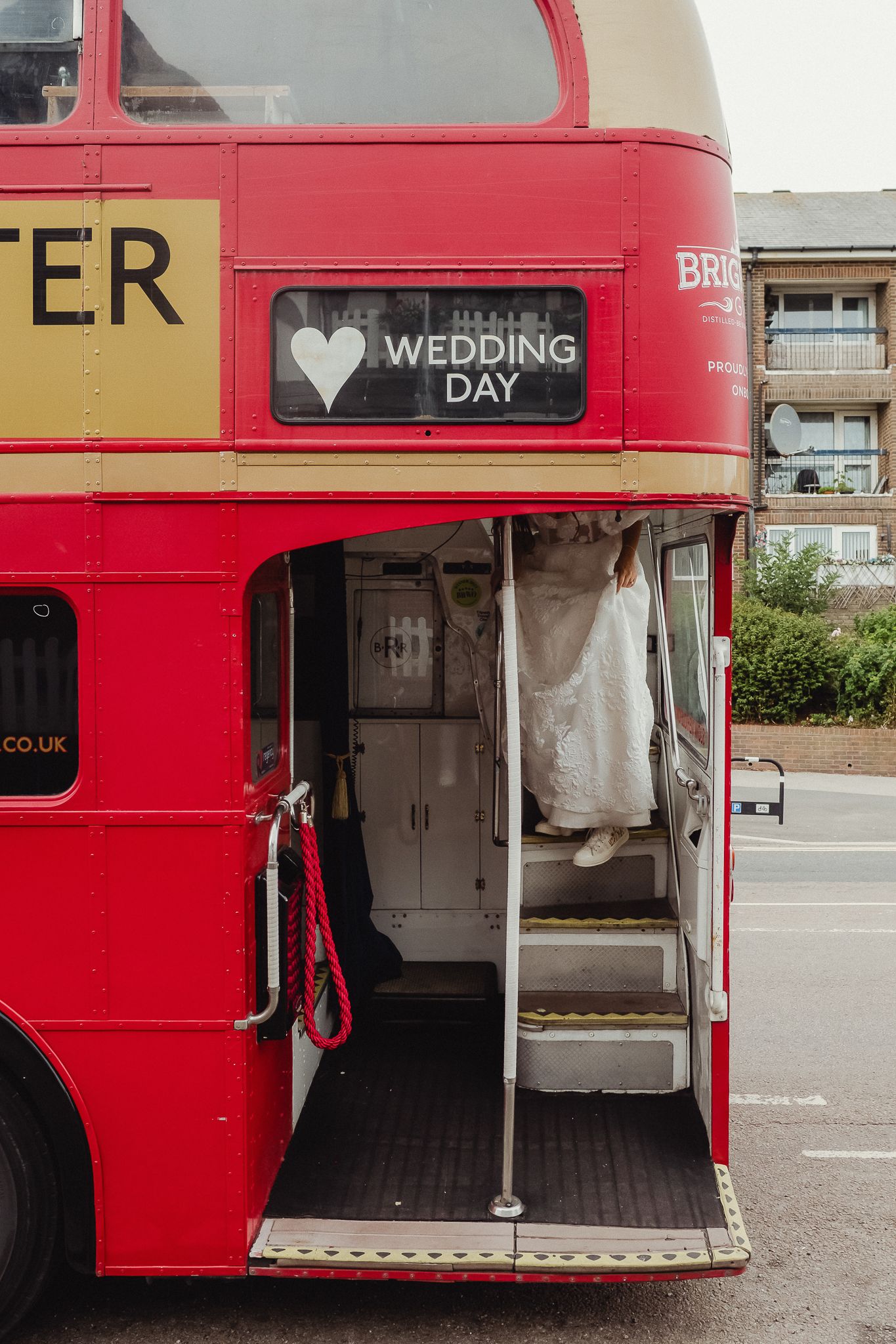 Close-up views of a red vintage double decker bus decorated for a wedding with white fabric and signage.