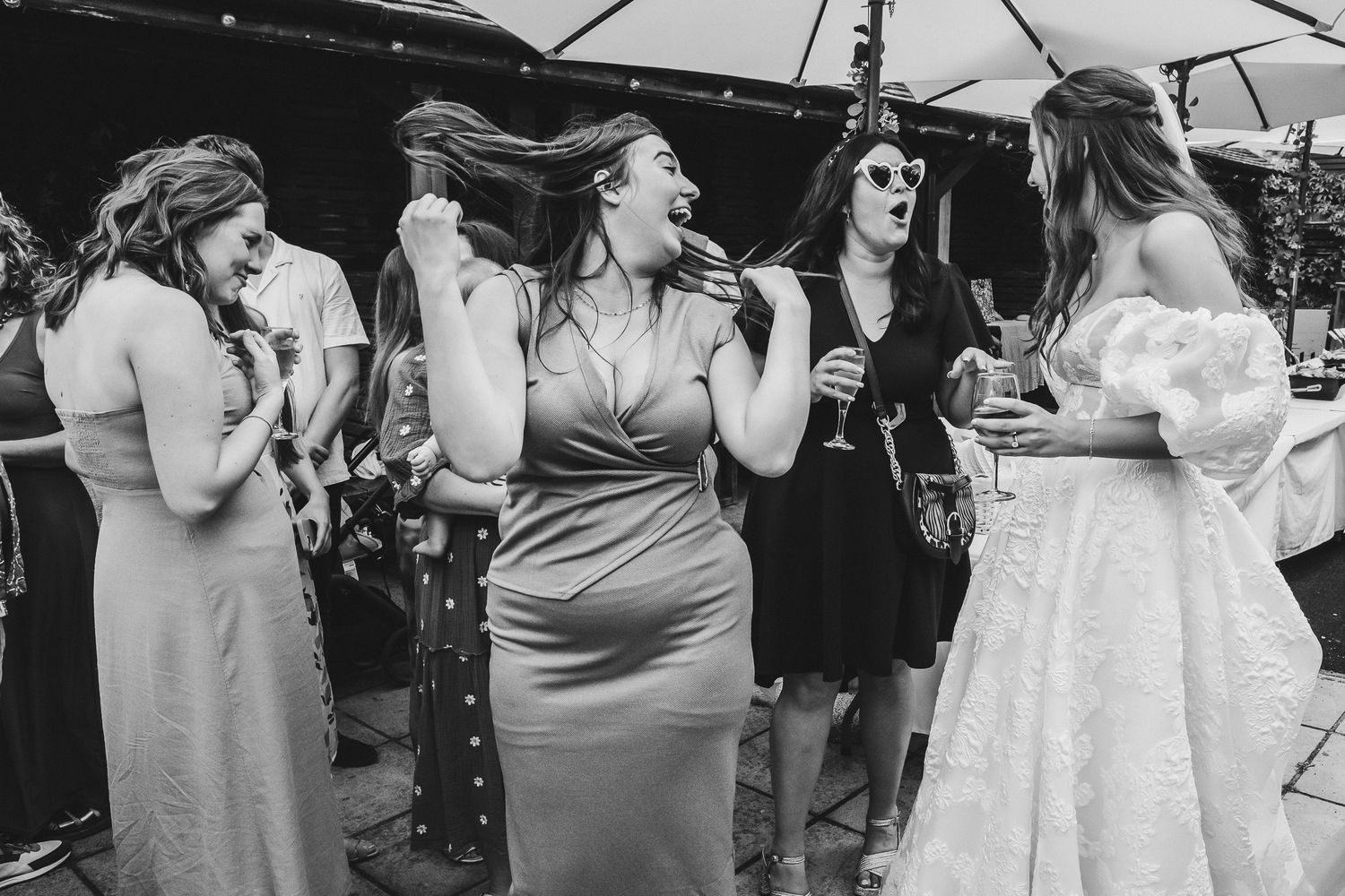 A group of wedding guests dance and celebrate together on an outdoor dance floor during a reception celebration.