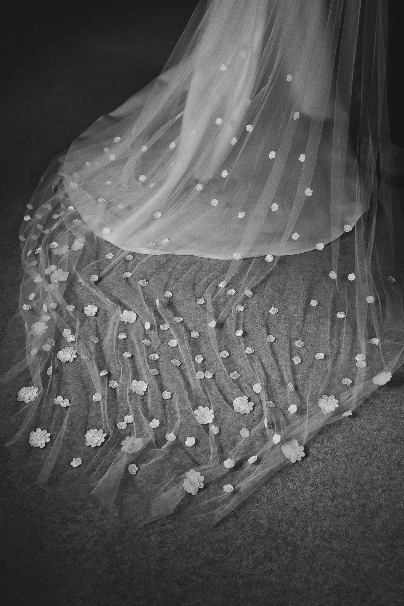 A delicate wedding veil with scattered floral appliques and pearls photographed in black and white.