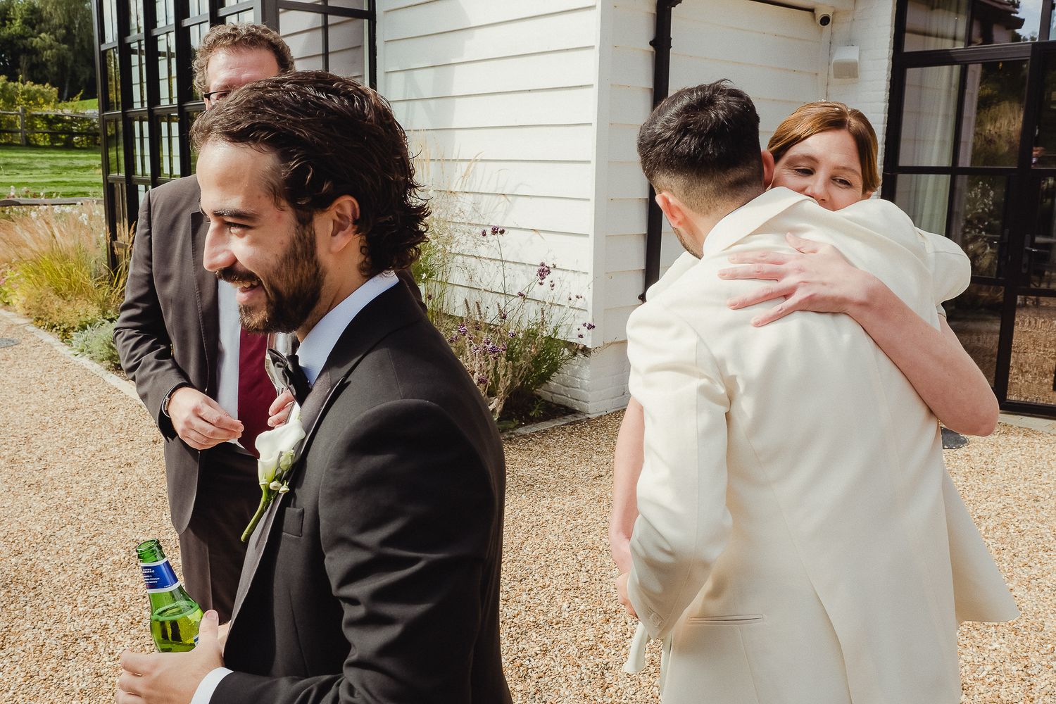 A sequence of emotional wedding moments captured in black and white showing hugs and embraces outside a building.
