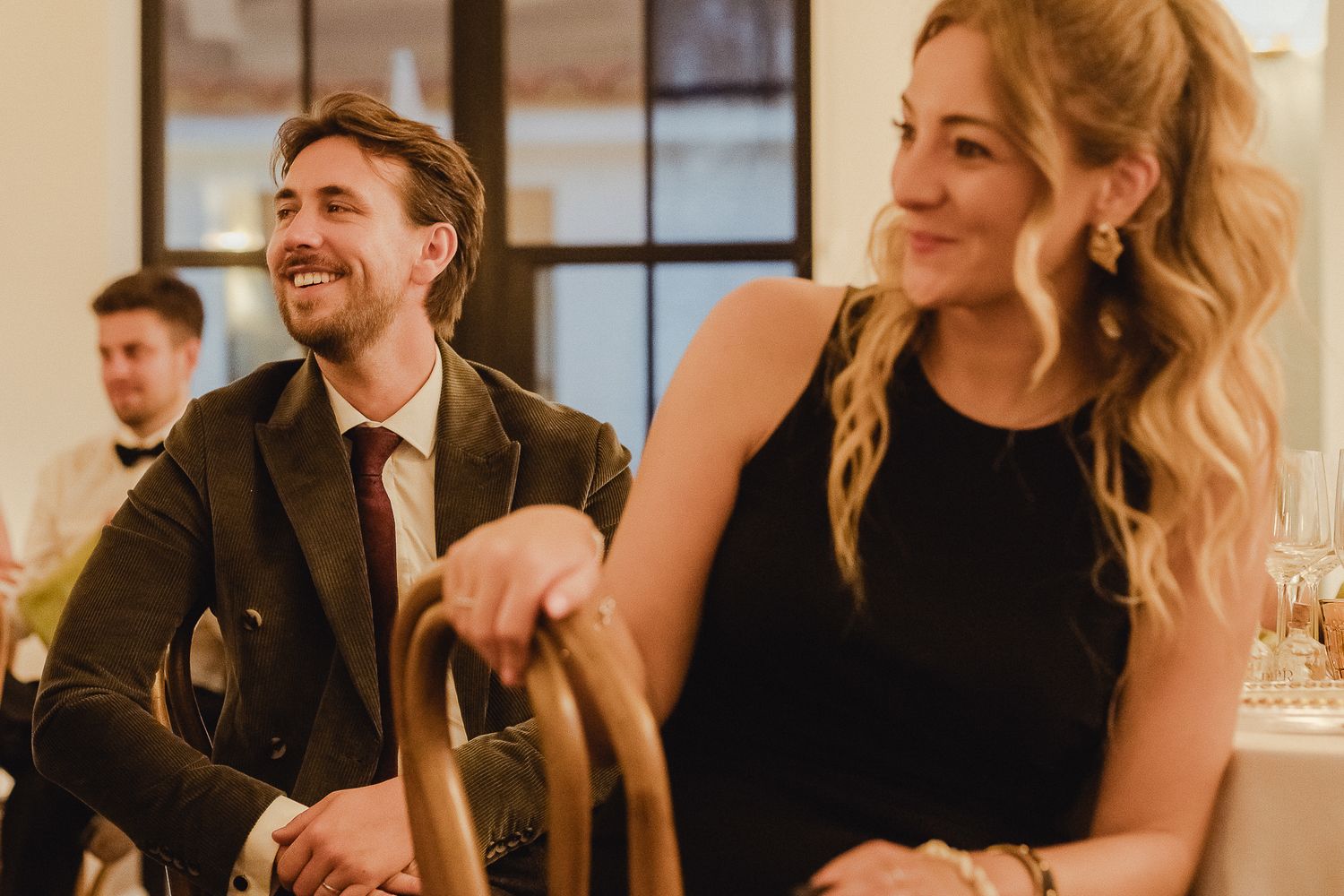 People enjoying themselves at an elegant indoor event, with warm lighting and wine glasses on the table.