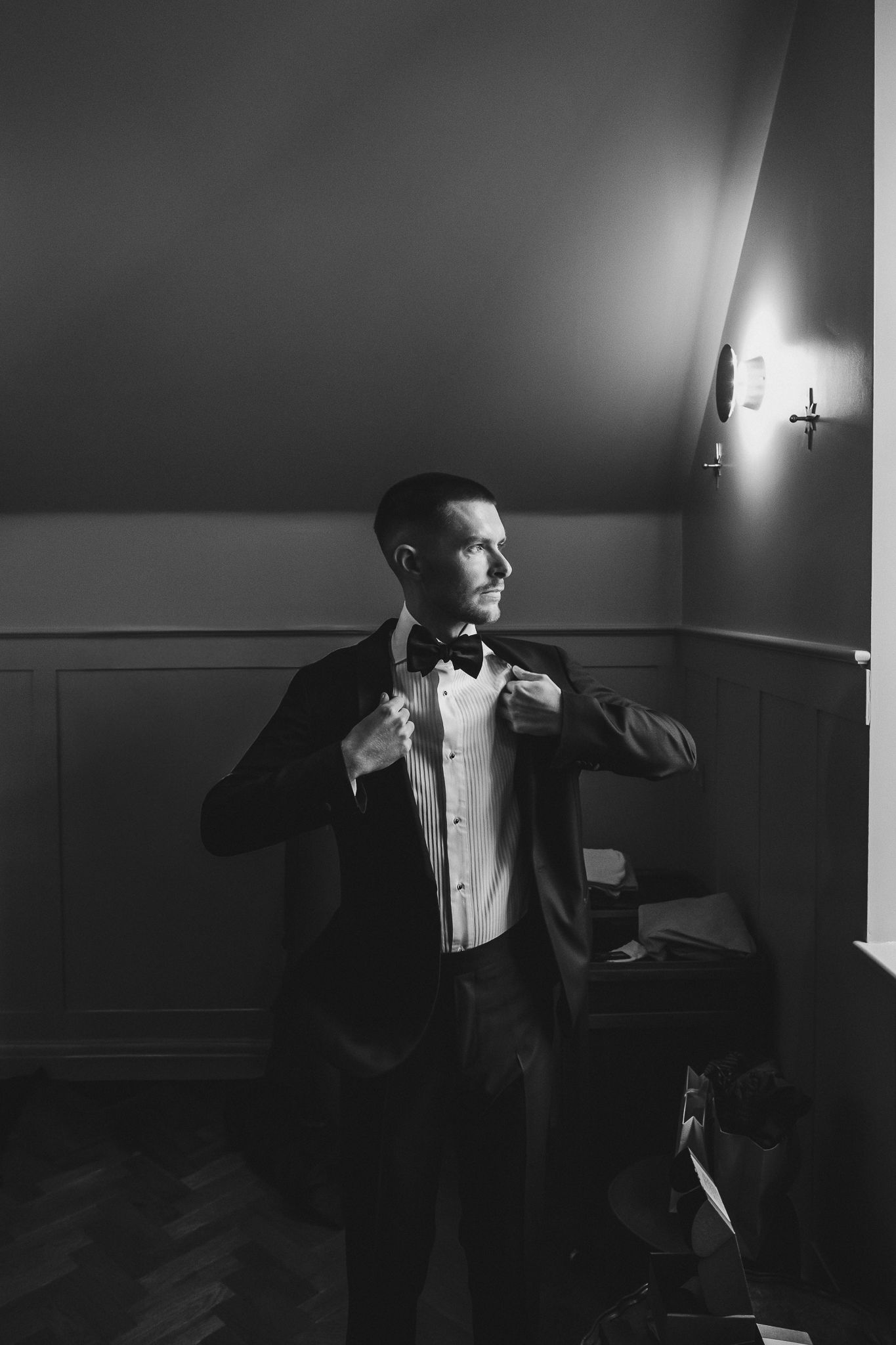 Dramatic black and white sequence shows a person in formal attire moving through dark hallway with moody lighting.