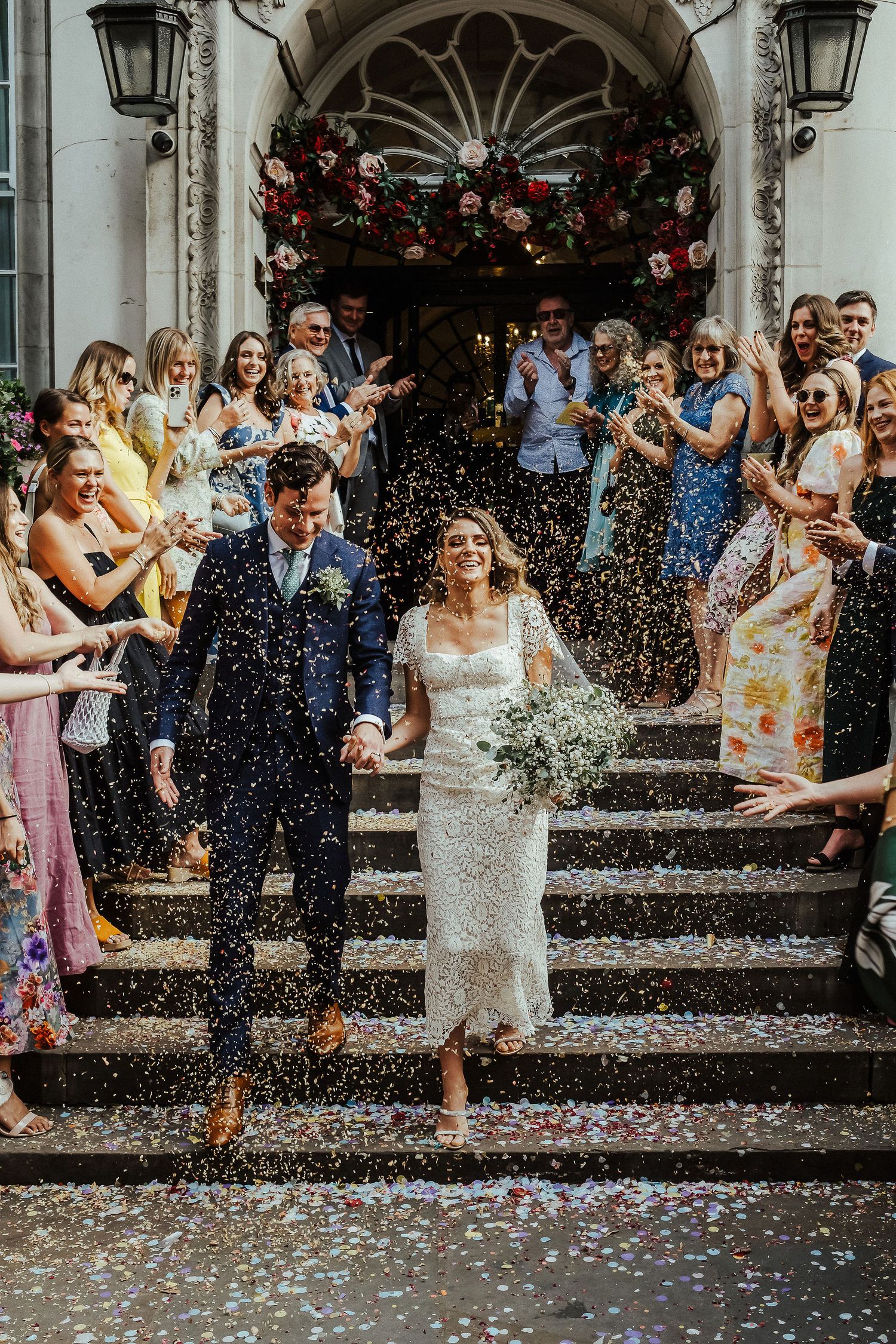 Wedding guests celebrate on stone steps throwing confetti in a joyful outdoor celebration sequence.