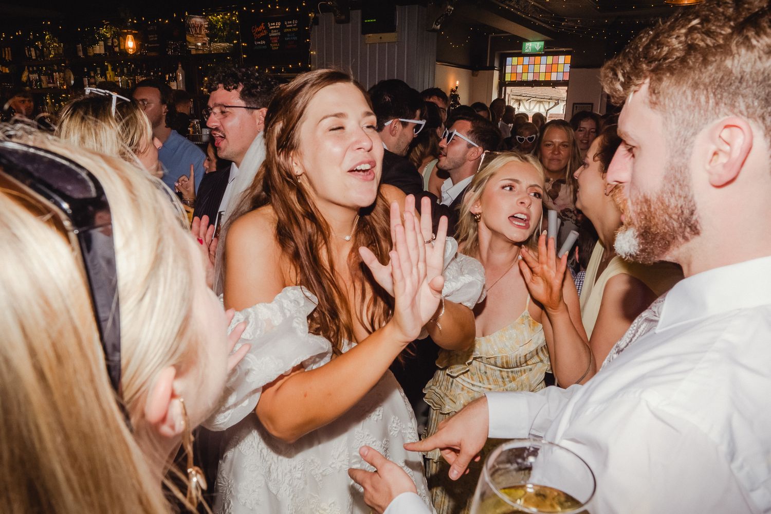A group of people dancing and celebrating at a lively wedding reception party with joyful expressions.