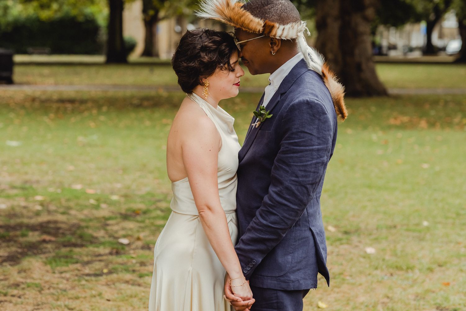 A couple shares an intimate moment during their wedding photoshoot in a scenic outdoor park setting.