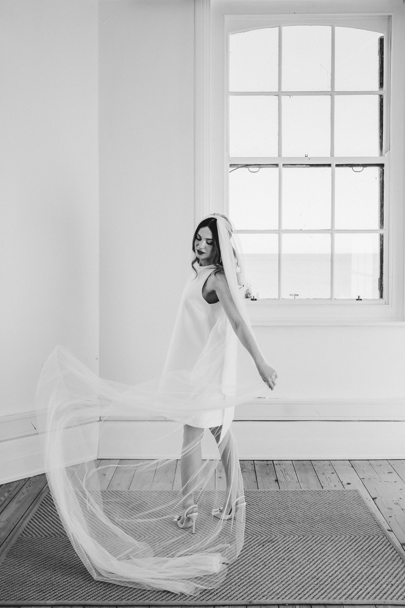 A black and white photo series showing a bride in flowing veil creating ethereal movement against a bright window backdrop.