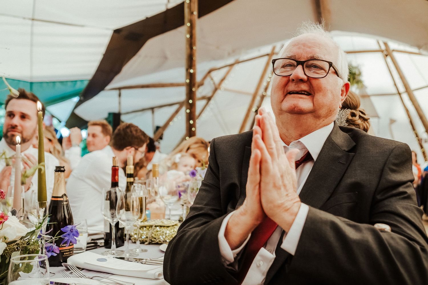 Wedding reception candids showing guests seated at tables under an elegant tent structure.