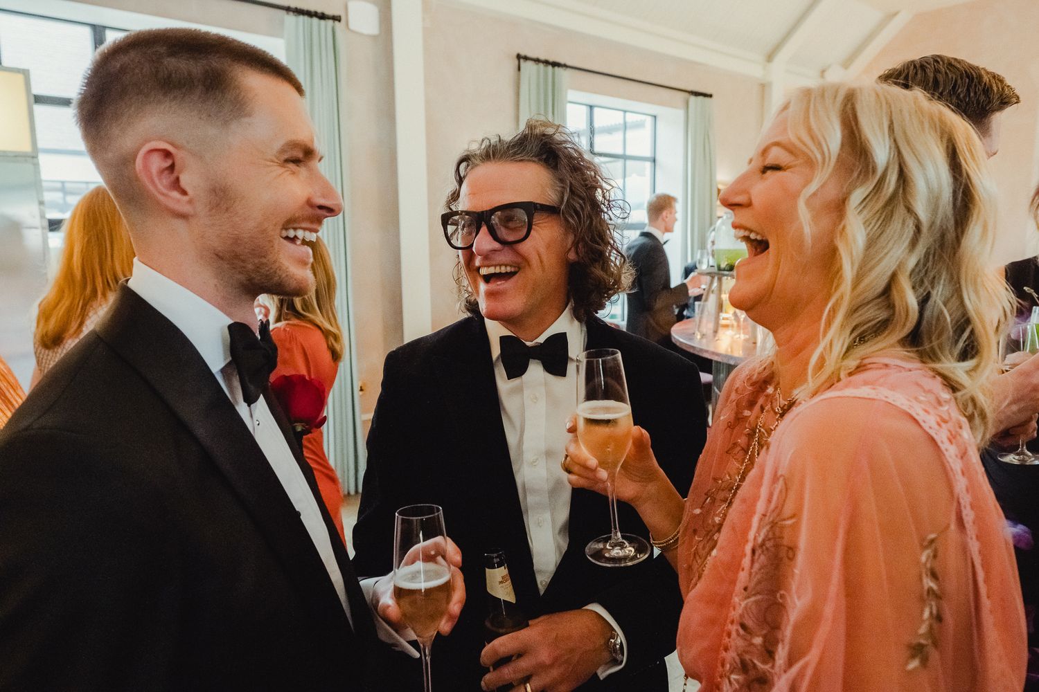 People enjoying drinks and conversation at an elegant indoor reception or social gathering.