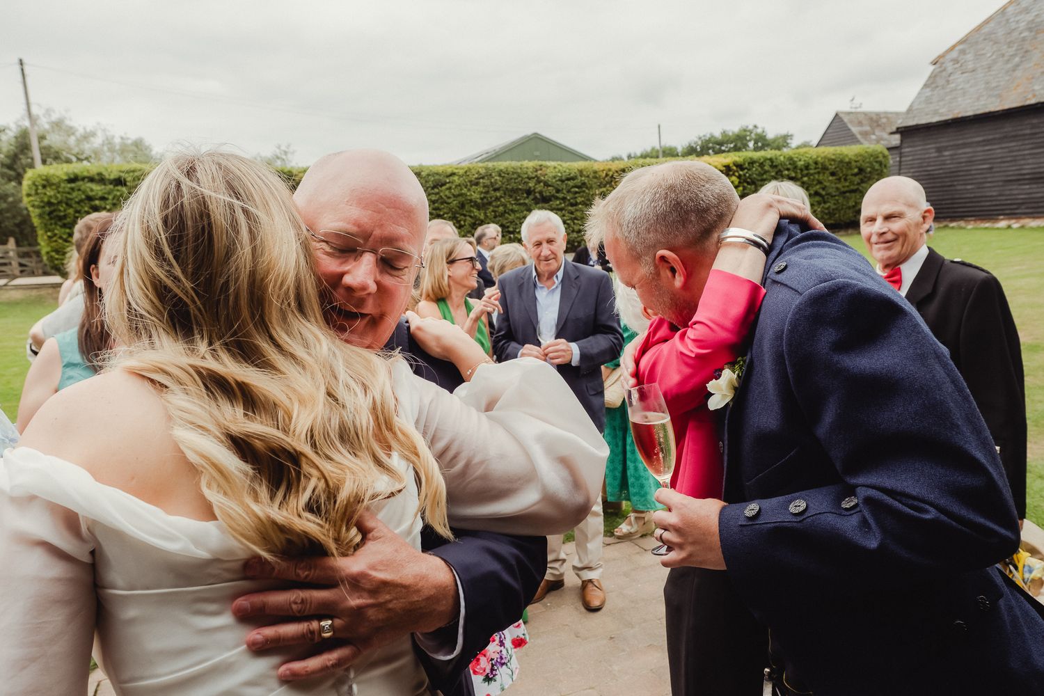 Wedding guests congratulate and embrace the newlyweds during an outdoor celebration.