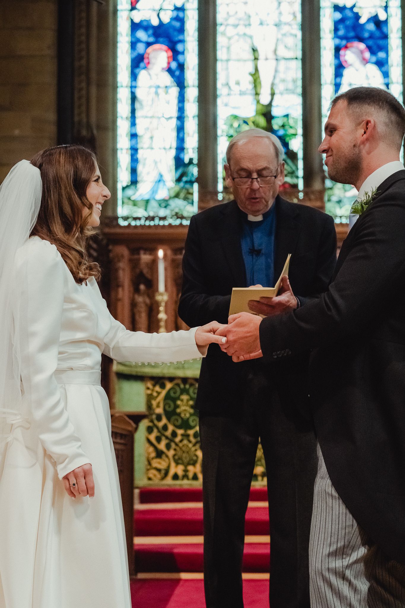 Wedding ceremony sequence showing exchange of rings and vows in a church with stained glass windows in background.