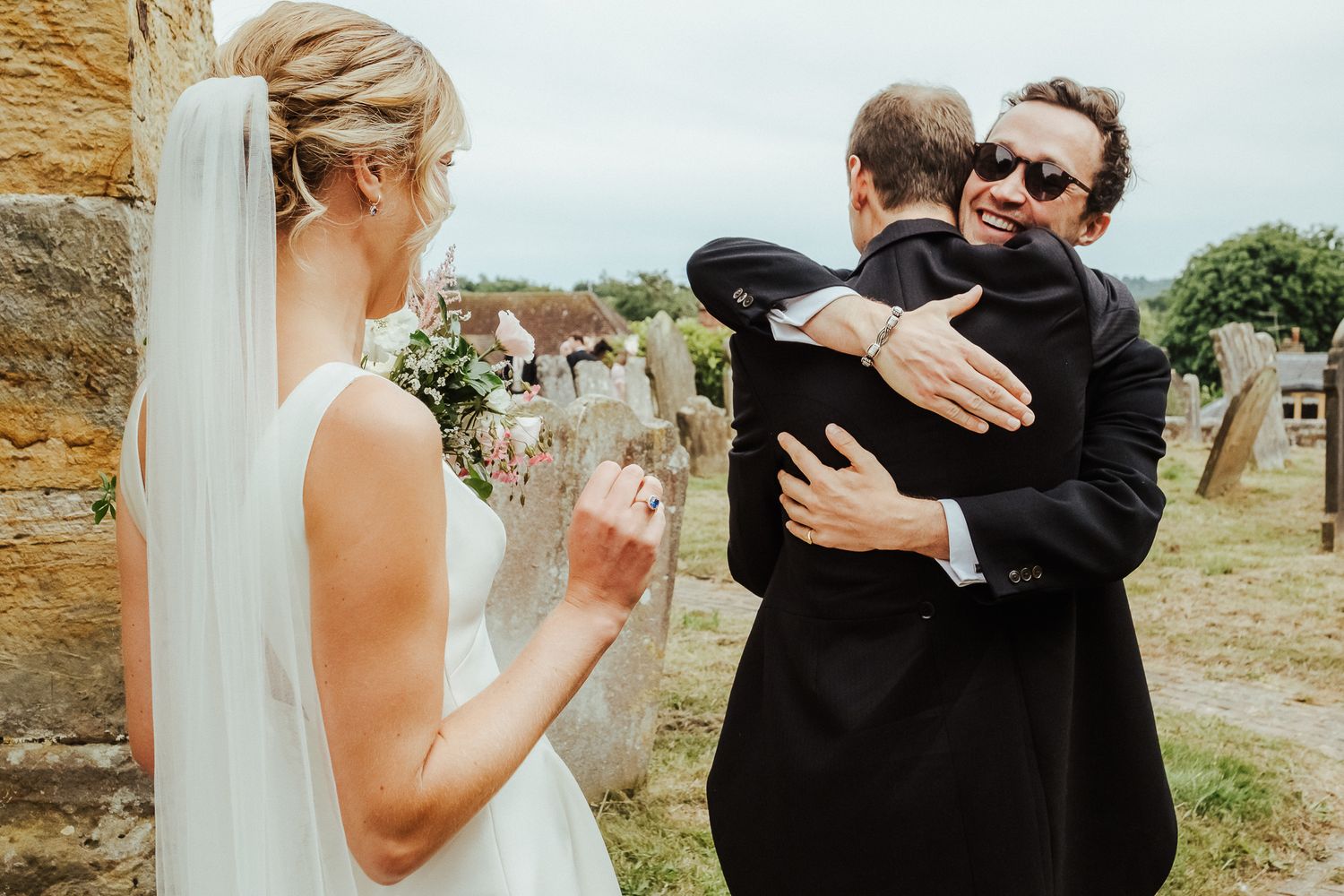 Emotional outdoor moment during a wedding celebration outside a stone church.