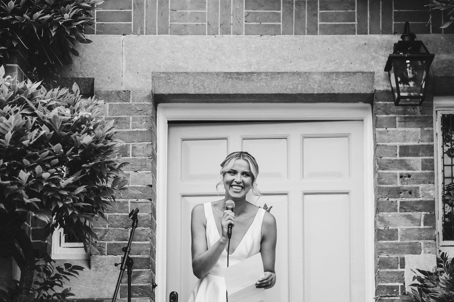A candid black and white portrait of someone laughing in front of a white door.