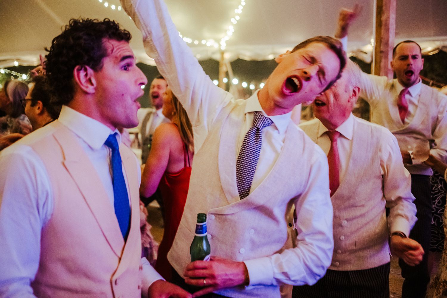 Energetic wedding guests celebrating and singing during the reception party.
