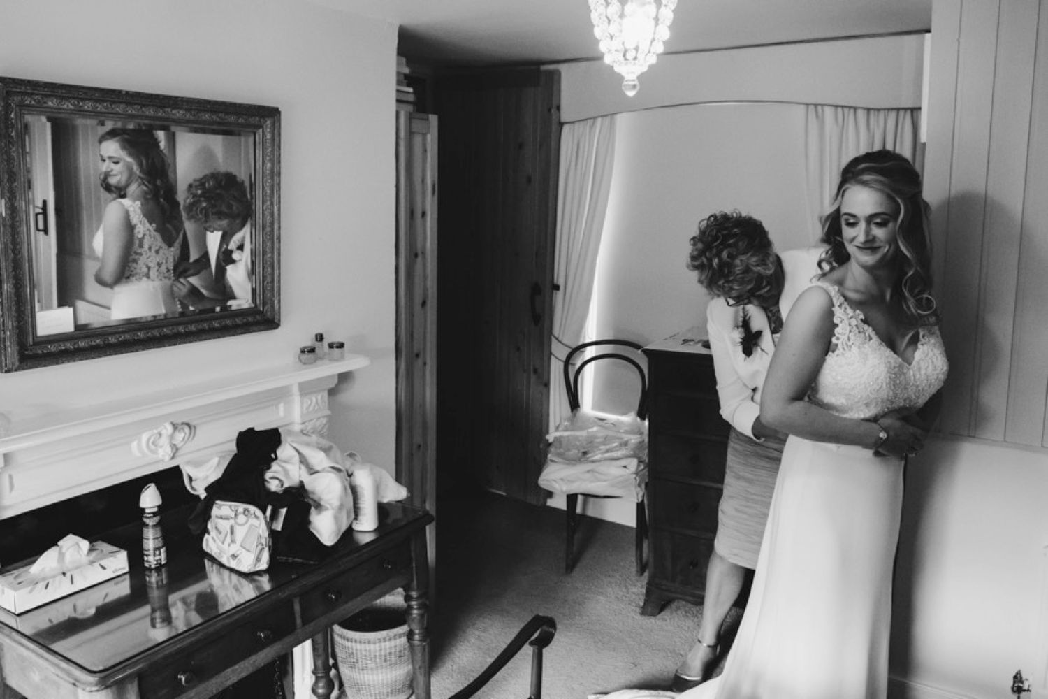 A black and white getting ready photo of wedding preparations with a bridal party in an elegantly decorated room.