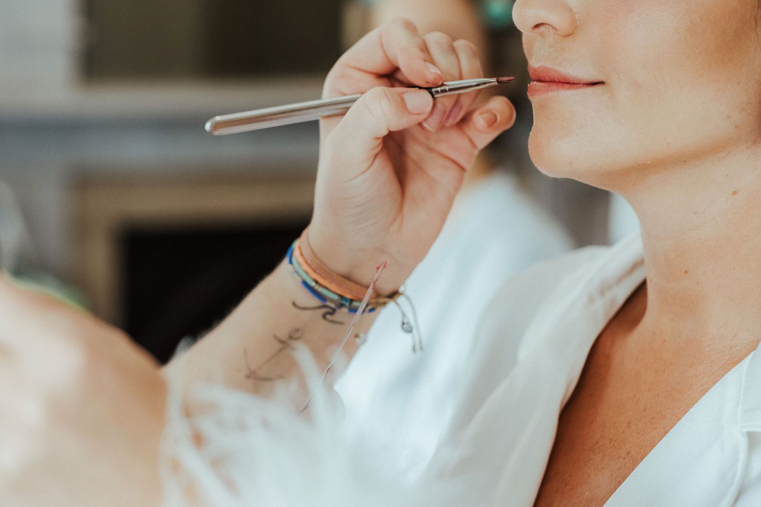 Close-up shot of makeup being applied with a brush during wedding preparations.