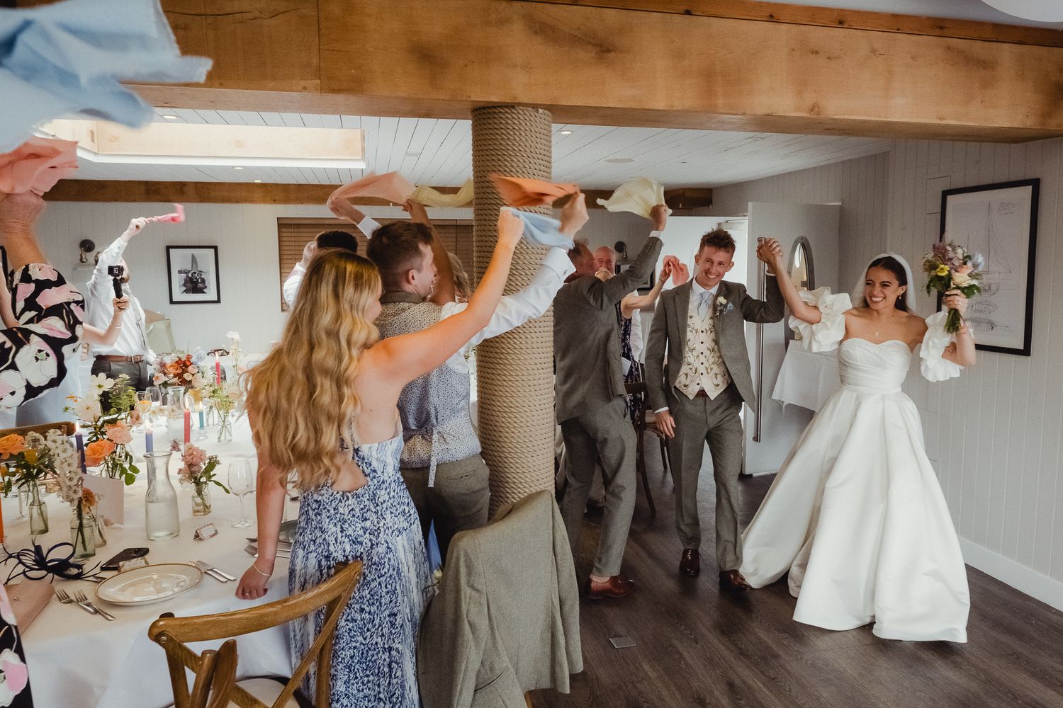 Wedding party members dance and celebrate during a joyful reception in a rustic wooden barn venue.