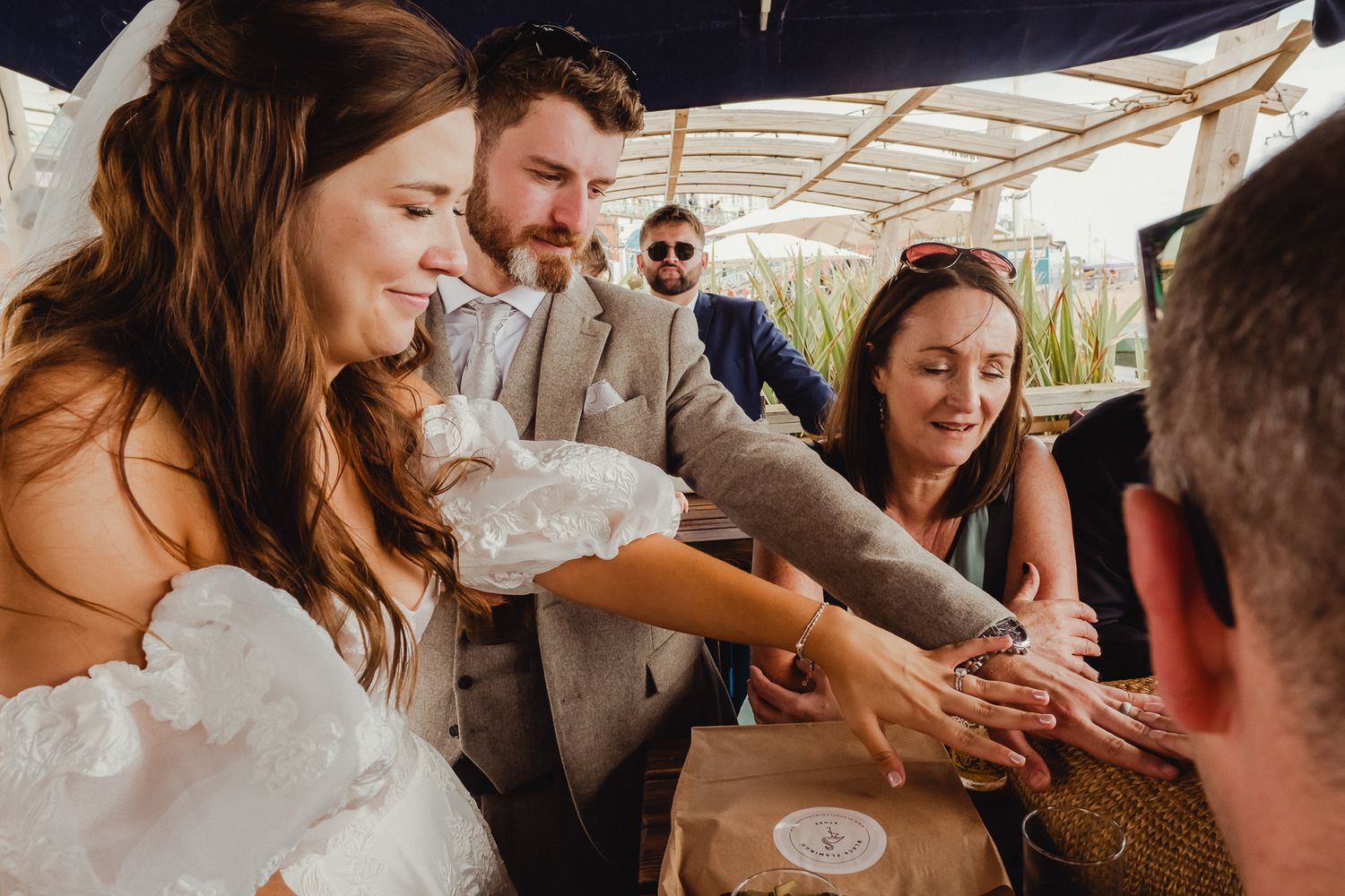 People celebrate and share joyful moments at an outdoor wedding reception under a white tent.