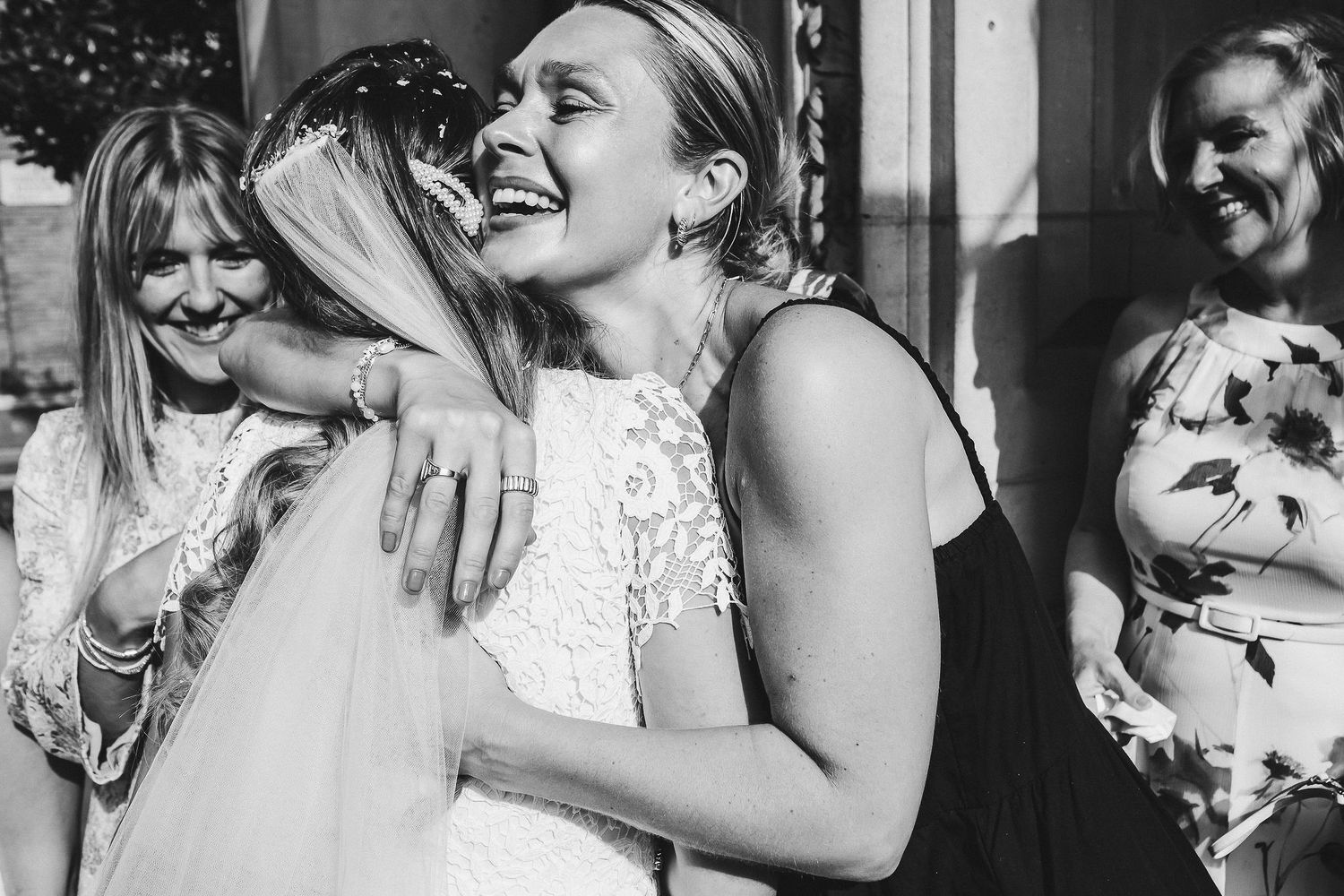 Black and white photo strip showing joyful candid moments of people laughing and embracing at a celebration.