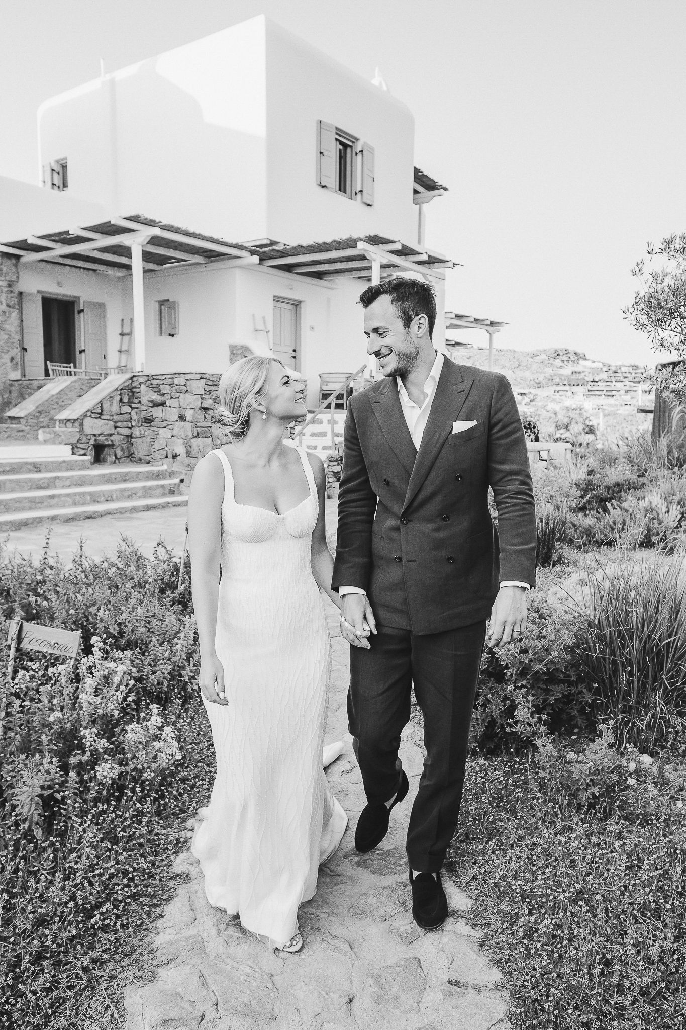 Black and white romantic outdoor wedding portraits of a couple walking through lush garden pathways.