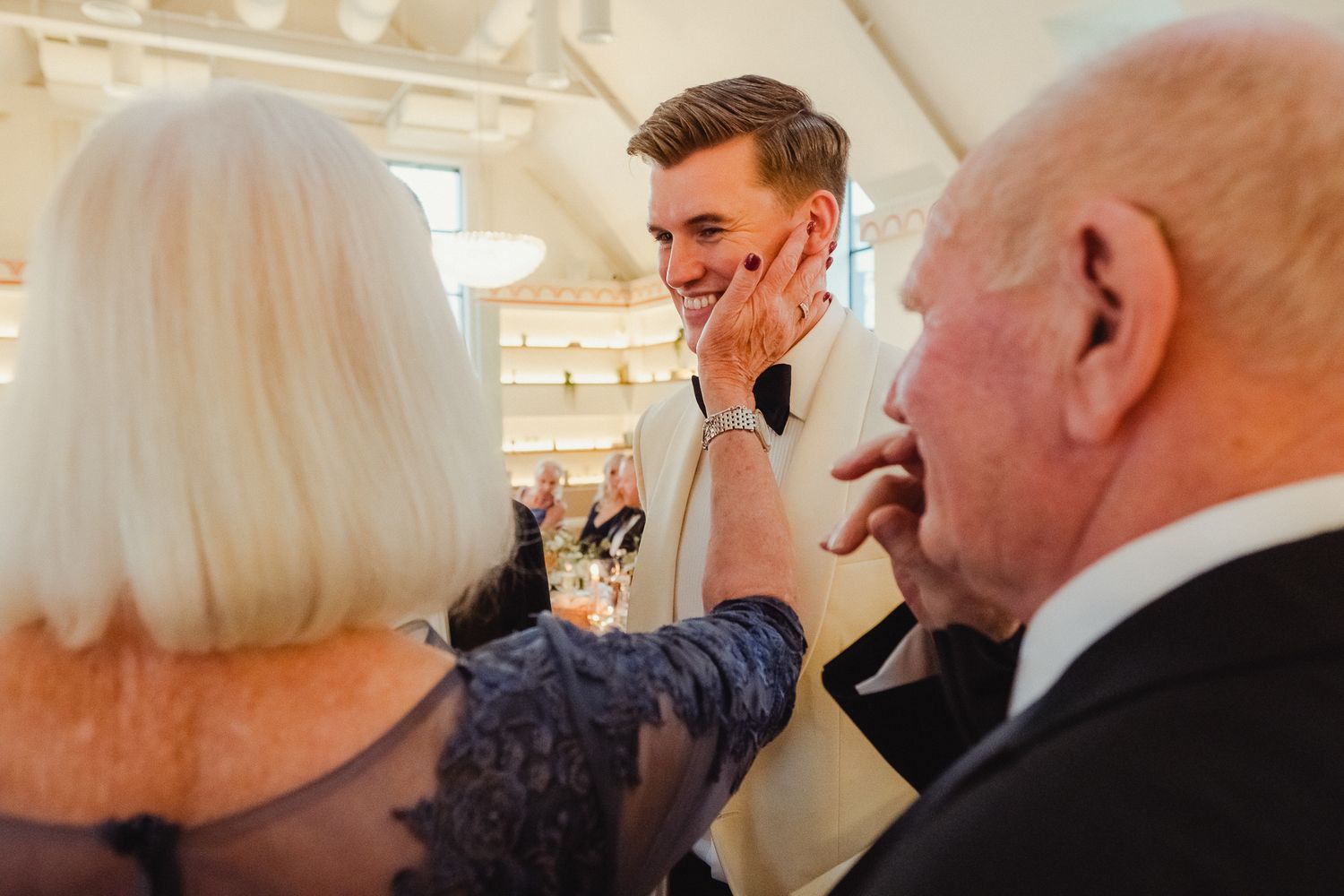 A candid moment of laughter and joy being shared between guests during a formal indoor celebration.