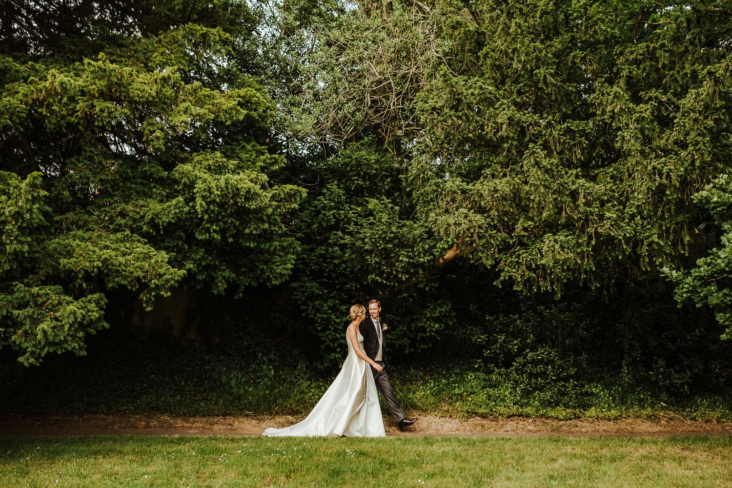 A wedding dress silhouette against lush green garden scenery.