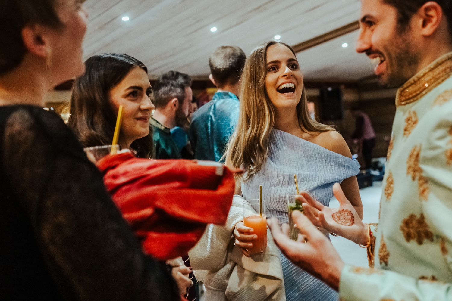 Party guests celebrate and dance together at a lively indoor reception event.