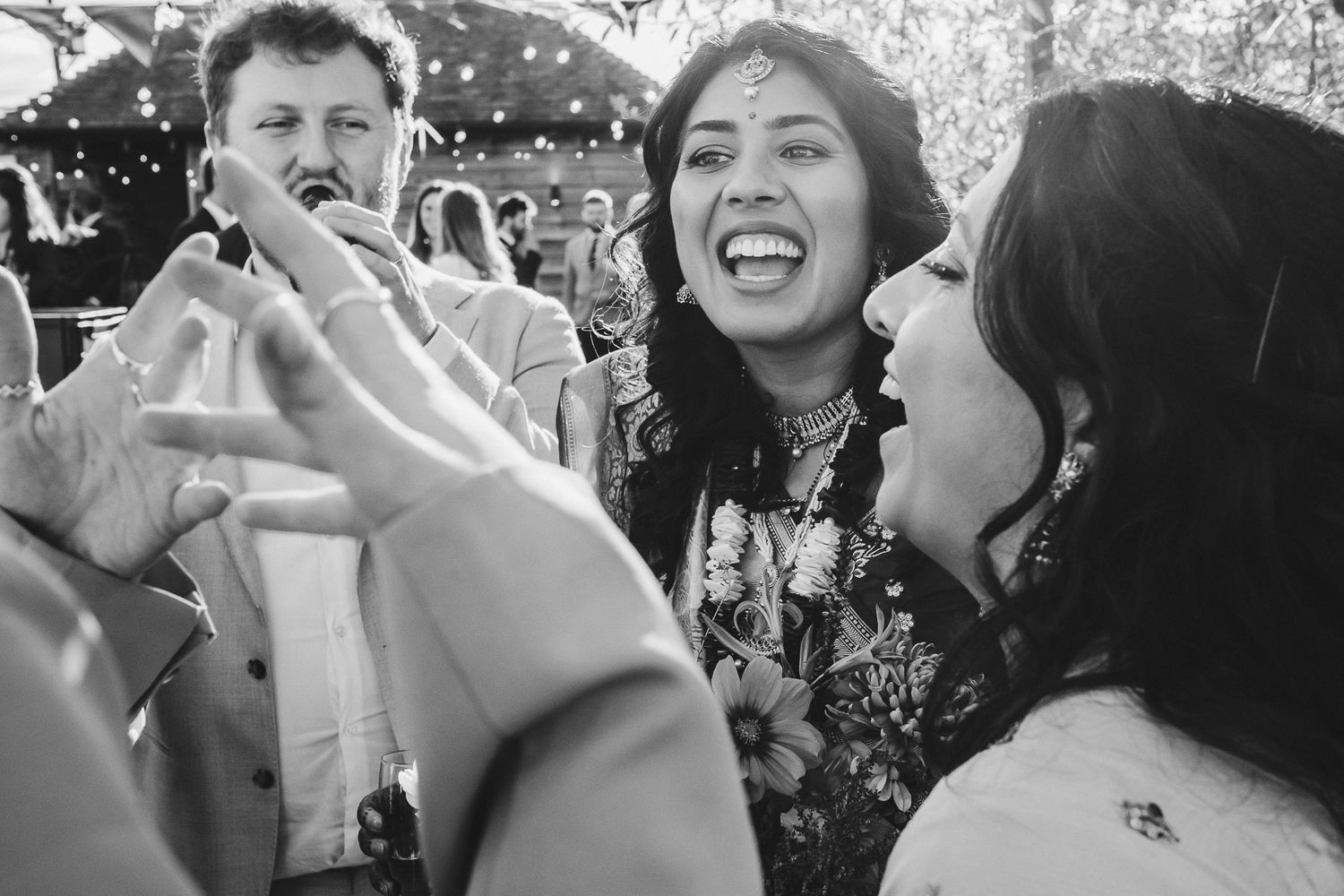 Black and white photo capturing spontaneous laughter and joy at a wedding celebration.