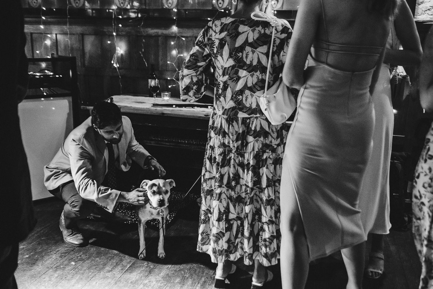 A black and white candid moment captured during a wedding reception showing guests in formal attire.