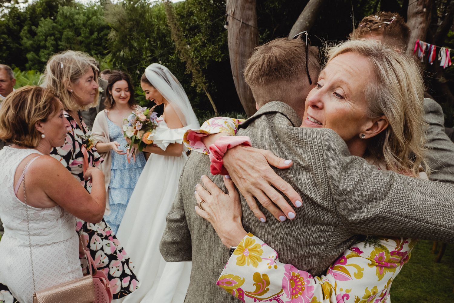People celebrating at an outdoor wedding reception with food and drinks at decorated tables in a garden setting.