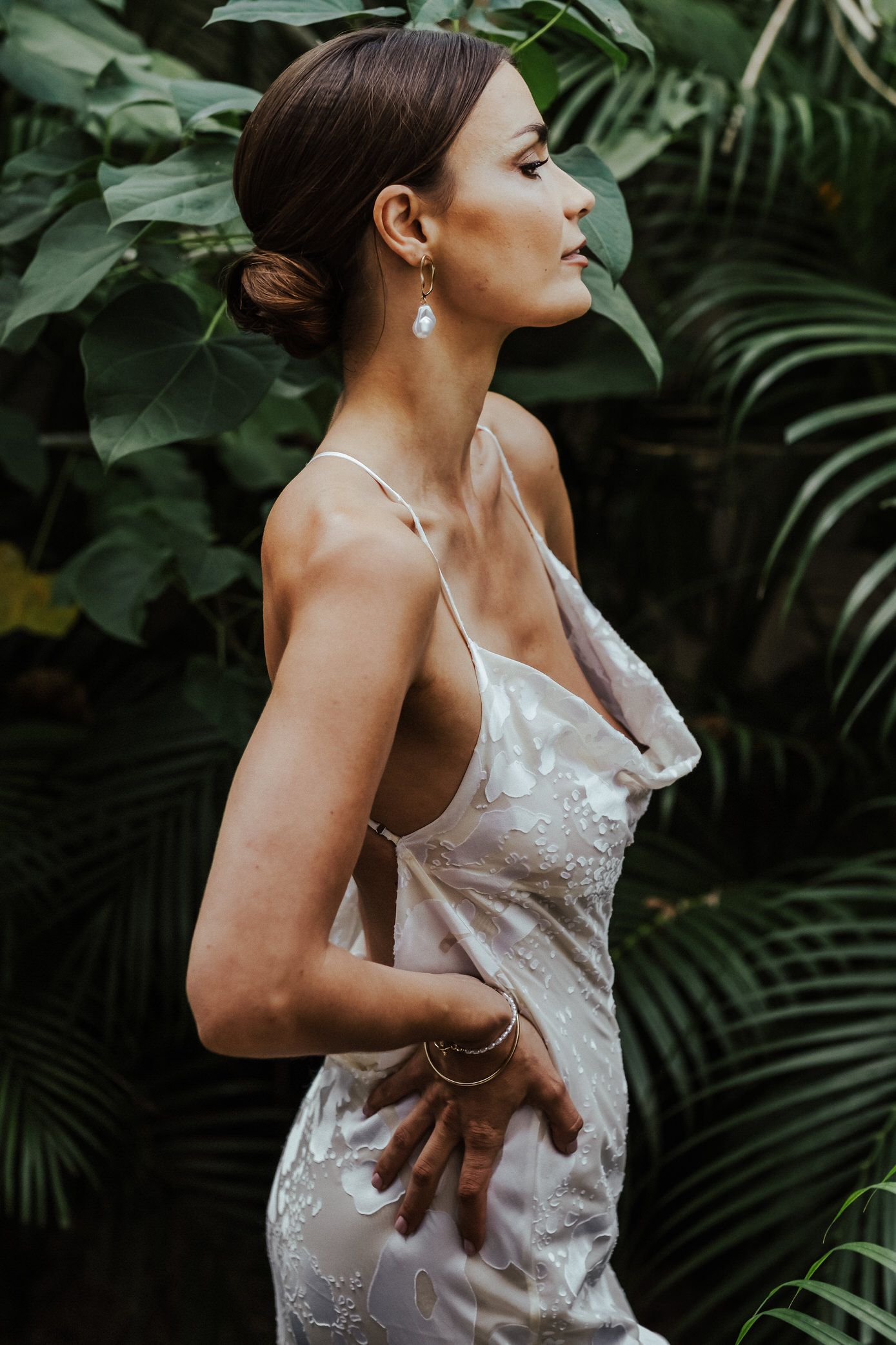 A white lace dress photographed in a series of close-up shots against lush tropical foliage background.