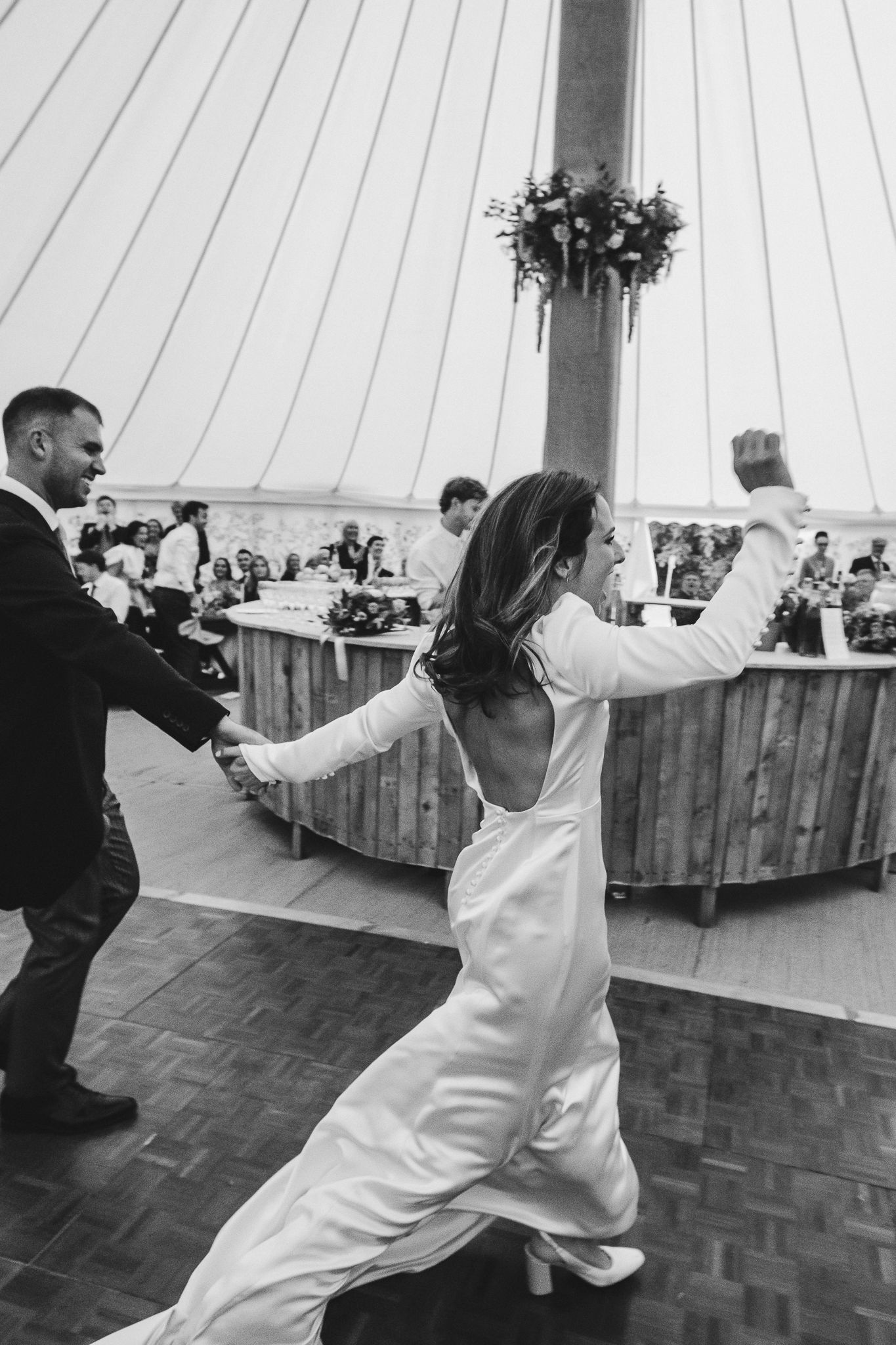 Black and white sequence of a couple dancing energetically on a parquet floor at a wedding reception.