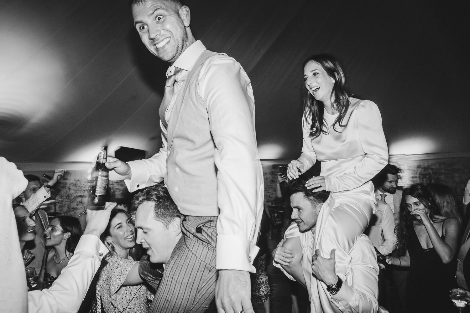 Black and white photos of a lively dance party with people dancing and celebrating on a crowded dance floor.