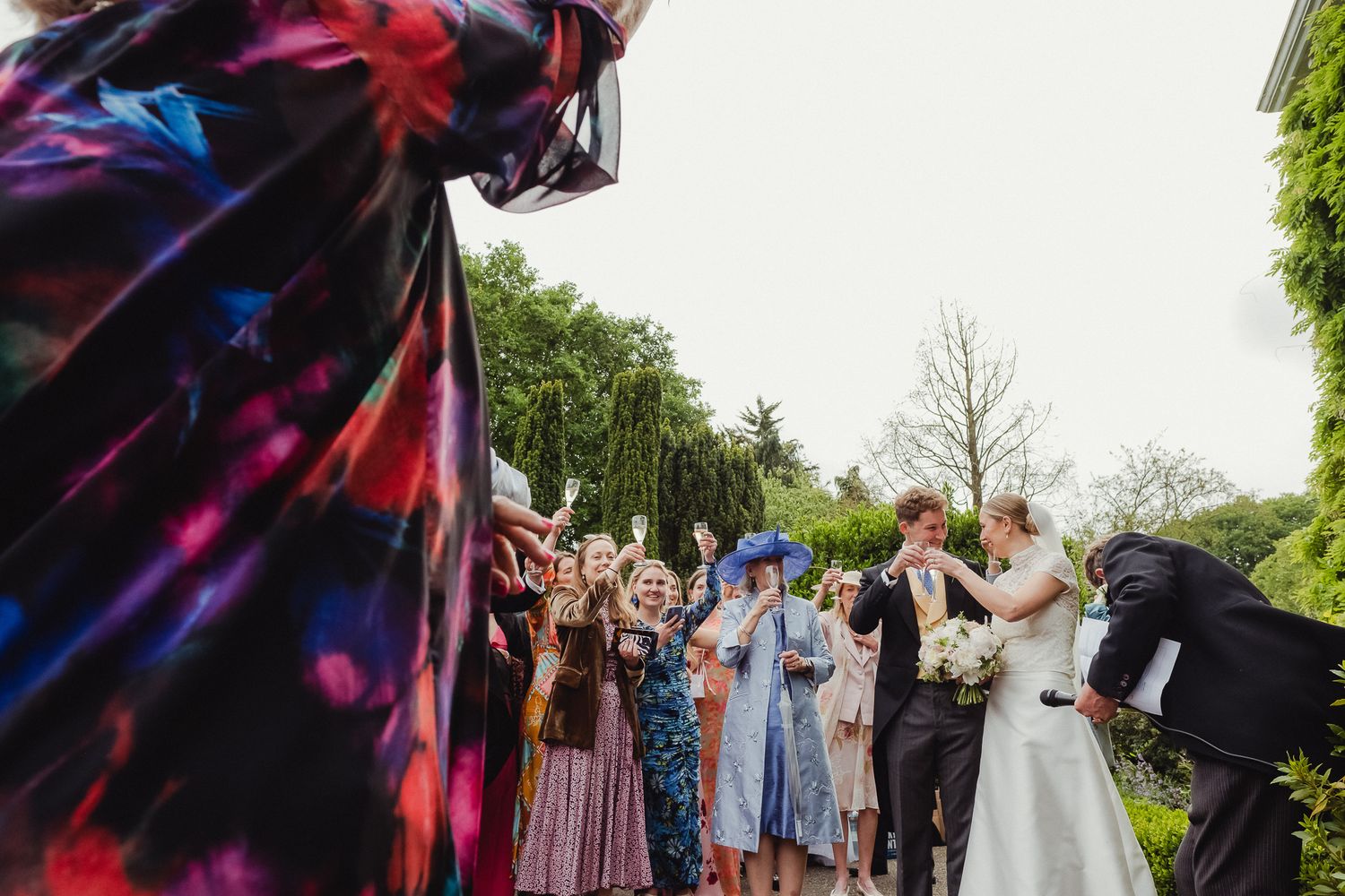 Wedding party throws colorful flower petals in celebration during outdoor ceremony.