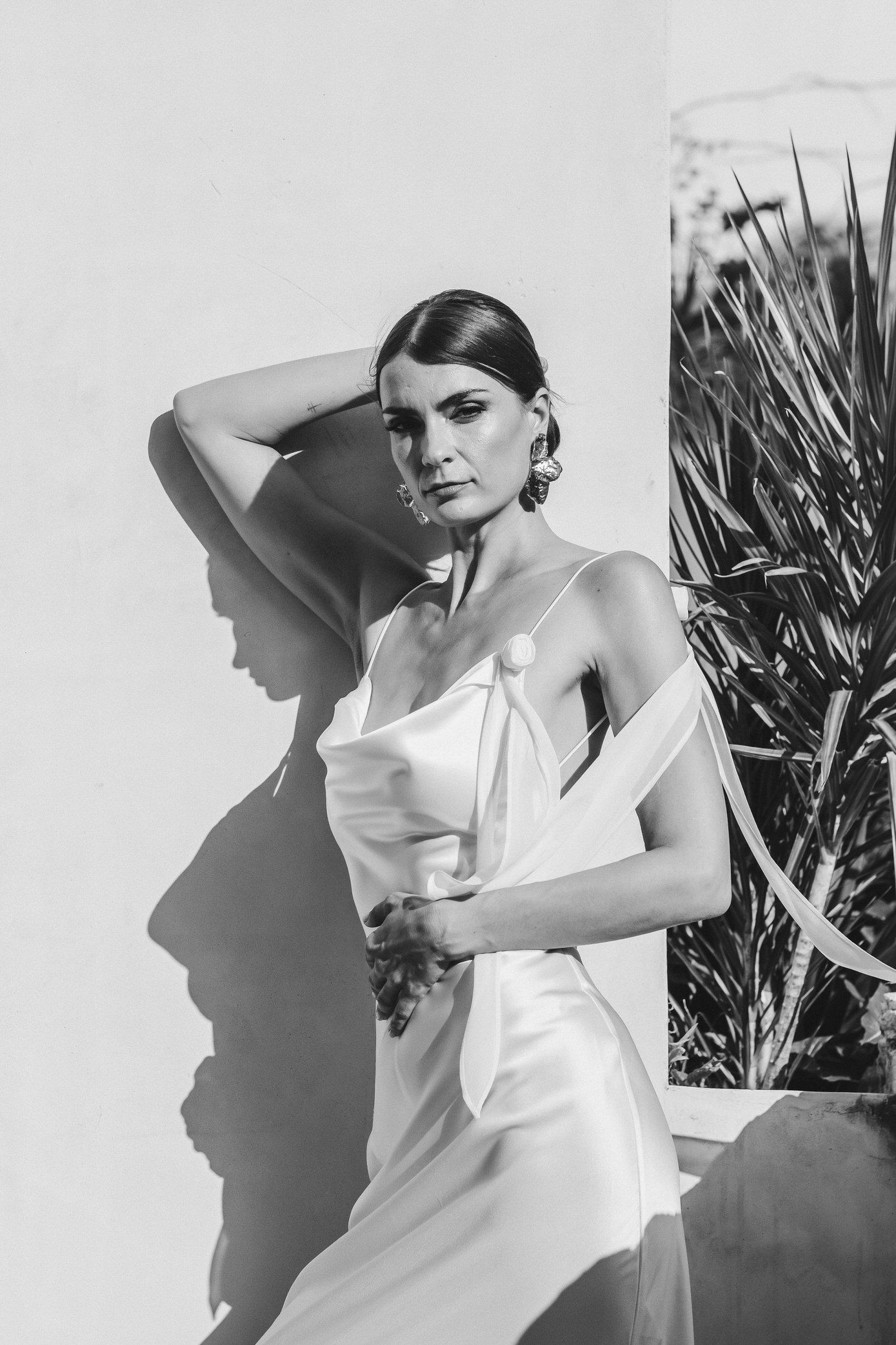 A series of artistic black and white fashion photographs showing a figure in white clothing against contrasting backgrounds.