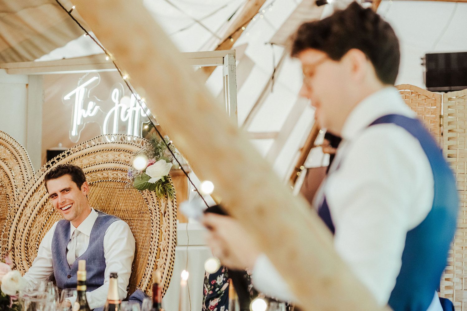 Wedding reception venue with neon signage and rattan decor during evening celebration.