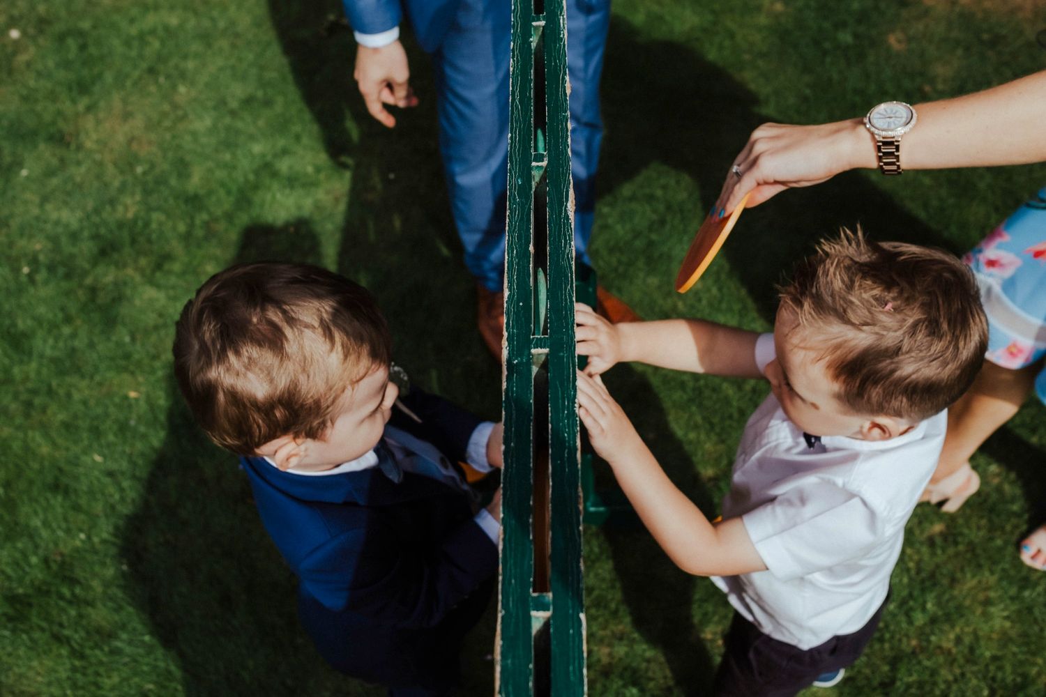 Children playing near a green garden fence during an outdoor event.