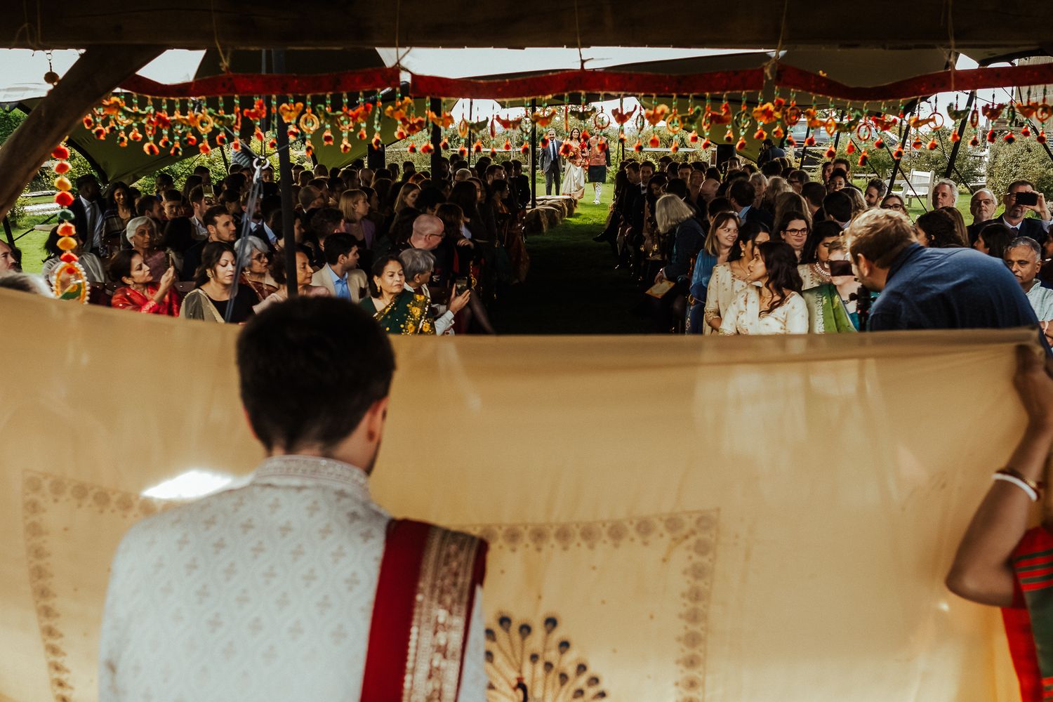 Guests gathered under a tent at a festive outdoor celebration with decorative banners.