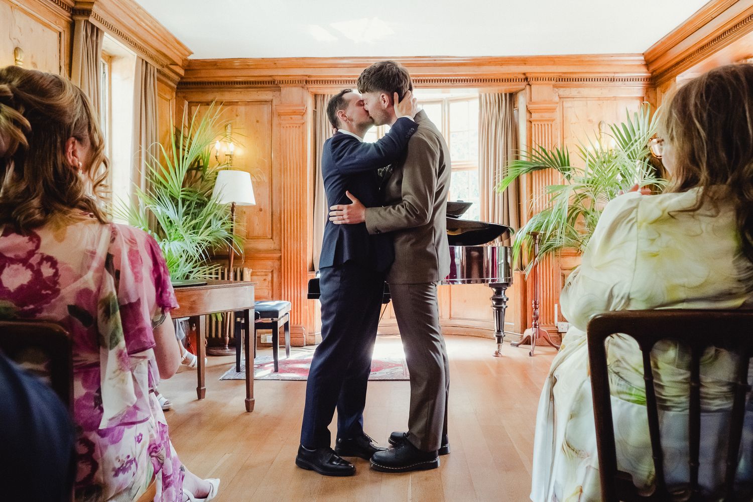 A romantic couple shares an intimate moment in a beautifully wood-paneled room with natural lighting.