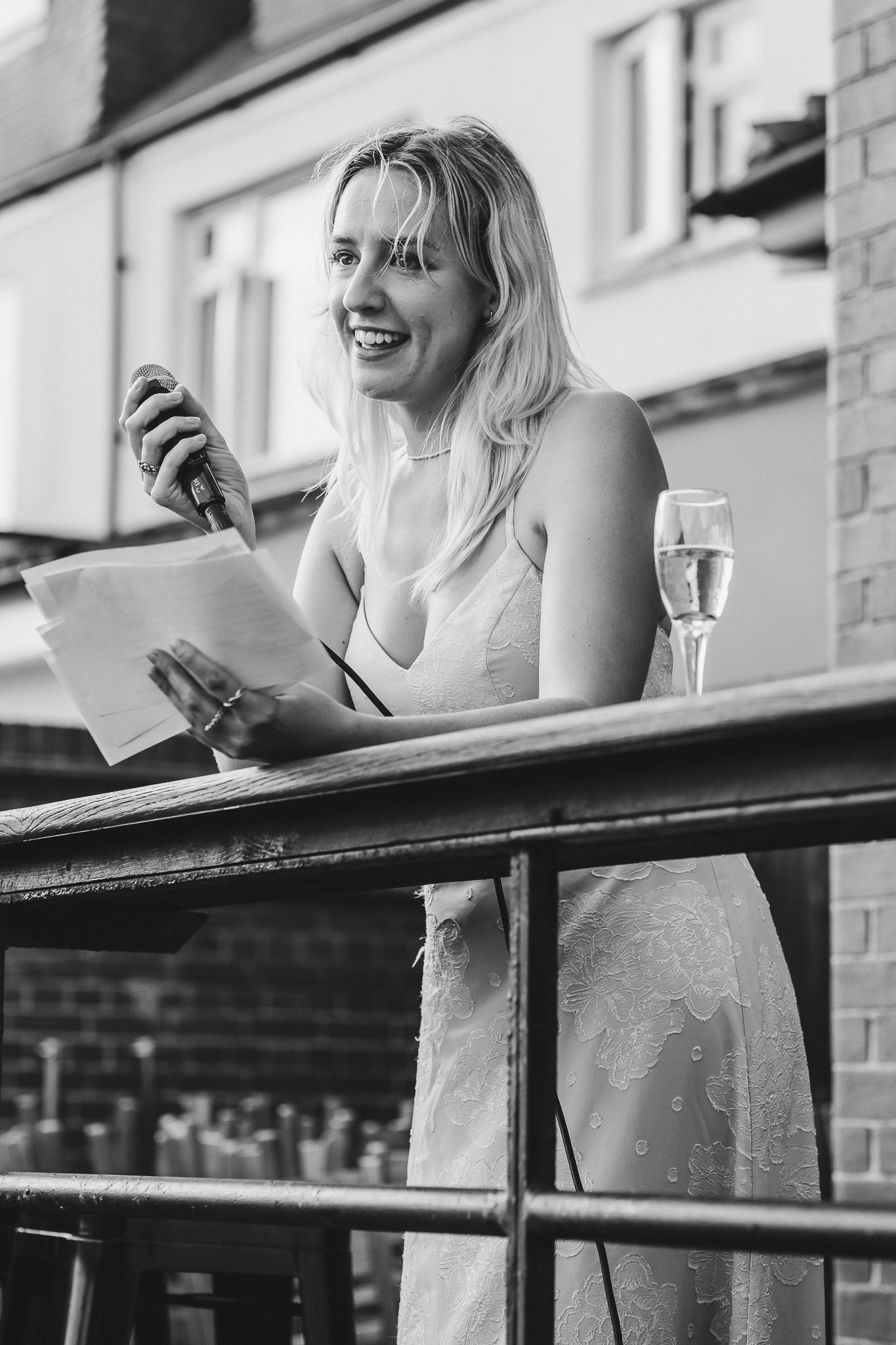 Black and white photo sequence showing a person enjoying wine and conversation on an outdoor balcony railing.