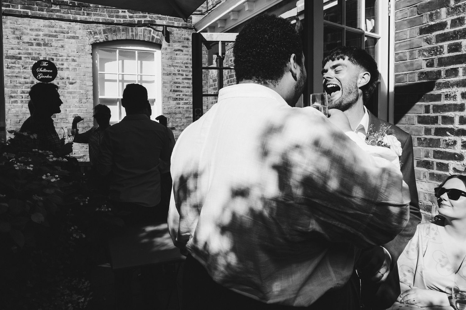 Black and white photo series showing people gathered outside a brick building with a blue plaque on the wall.