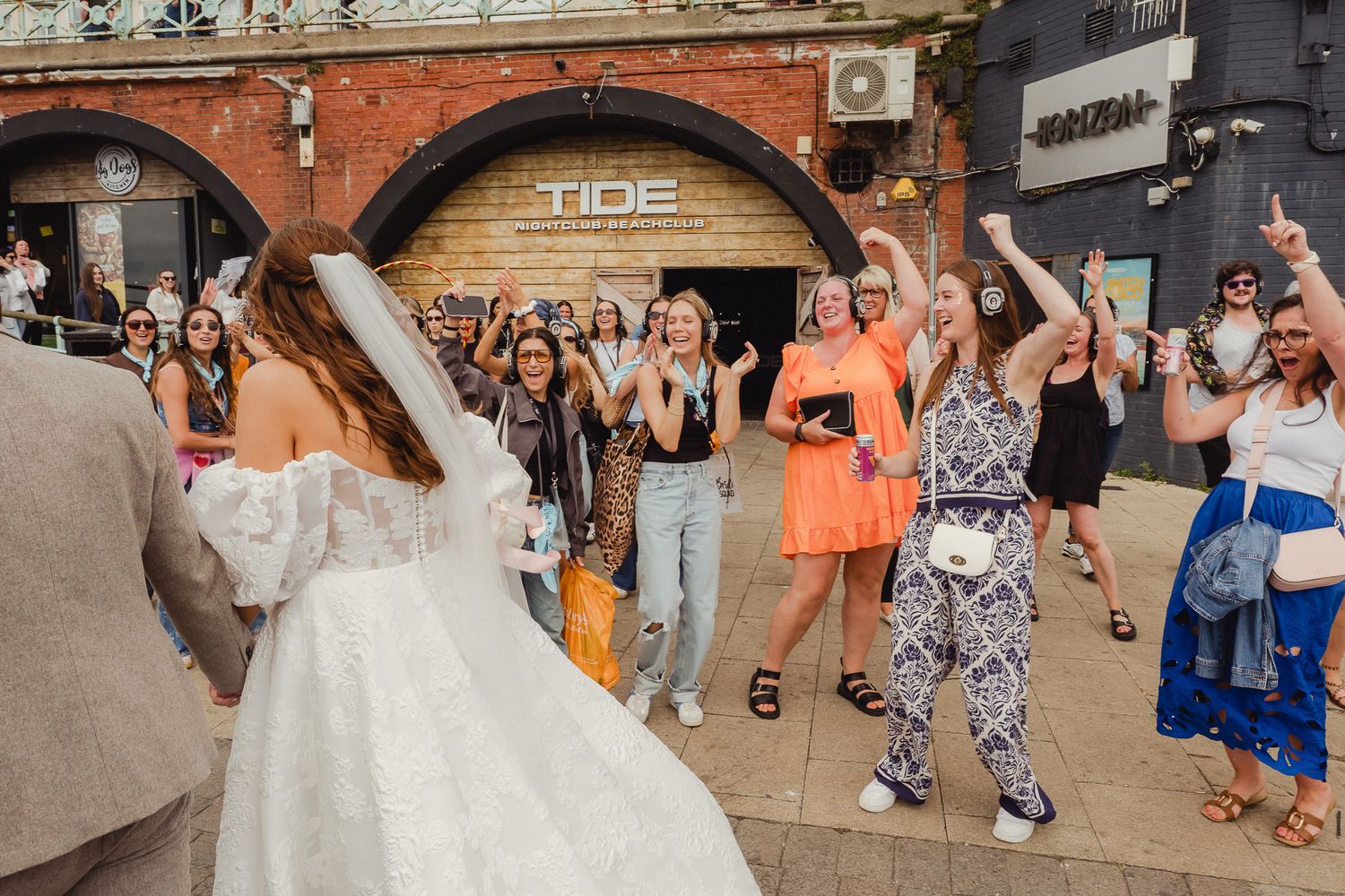 Wedding party celebrates with joyful dancing and festivities during outdoor reception at rustic venue.