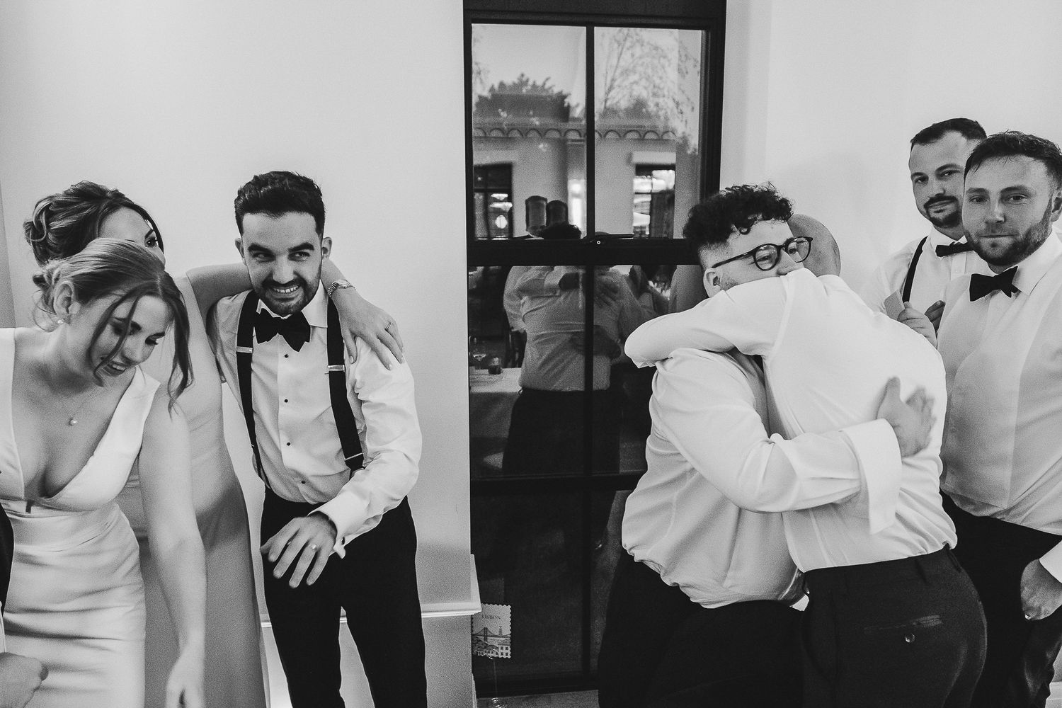 Black and white candid wedding photo showing emotional reactions during a special moment at the reception.
