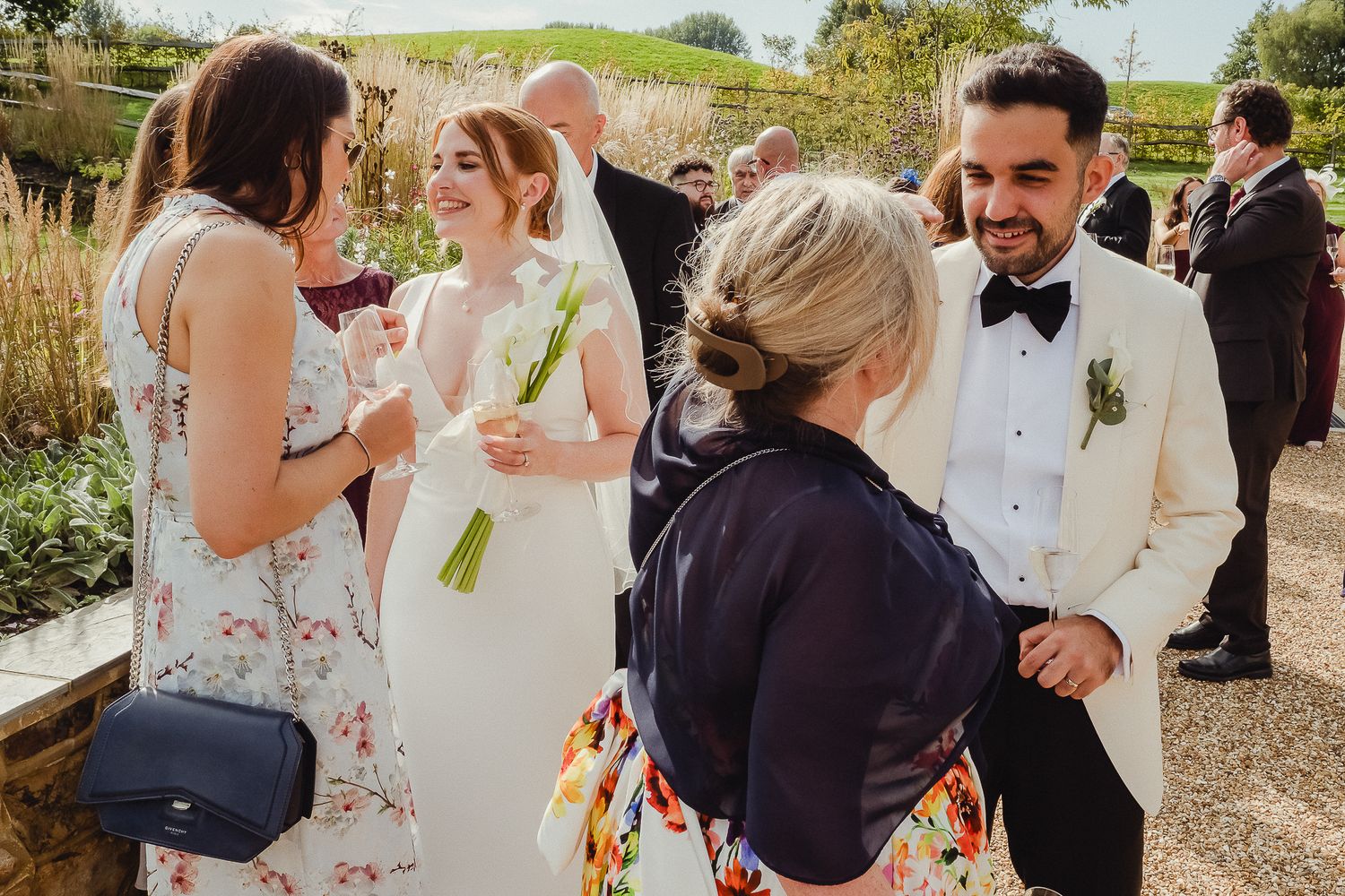 A joyous wedding celebration with guests mingling and dancing outdoors at a scenic venue on a sunny day.