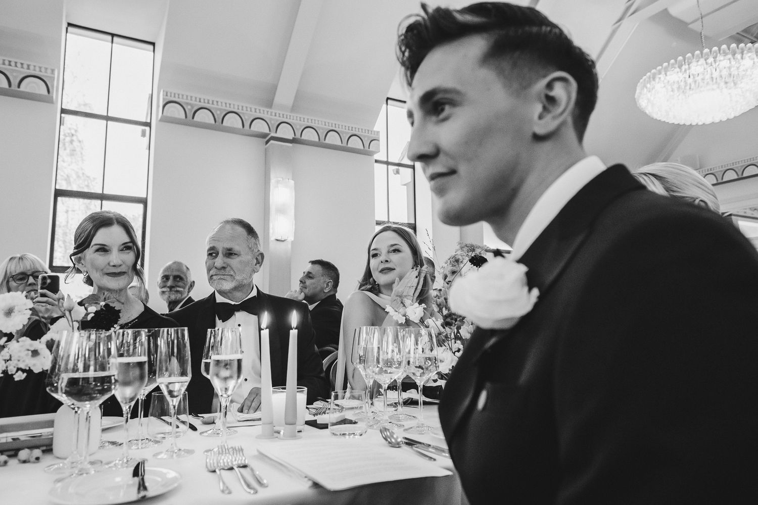 People seated at formal dining tables in black and white photograph series.